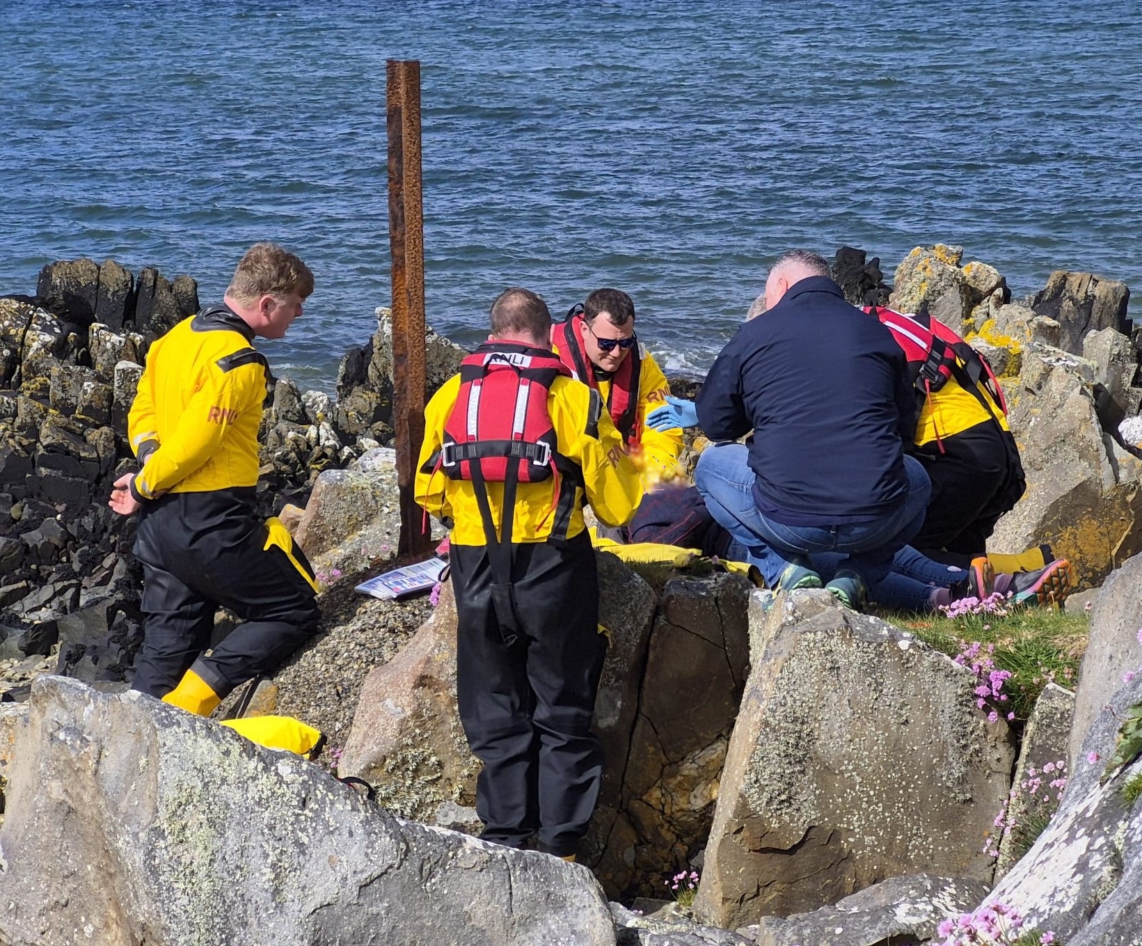 Crew completing a scenario based casualty care activity on a rocky shoreline