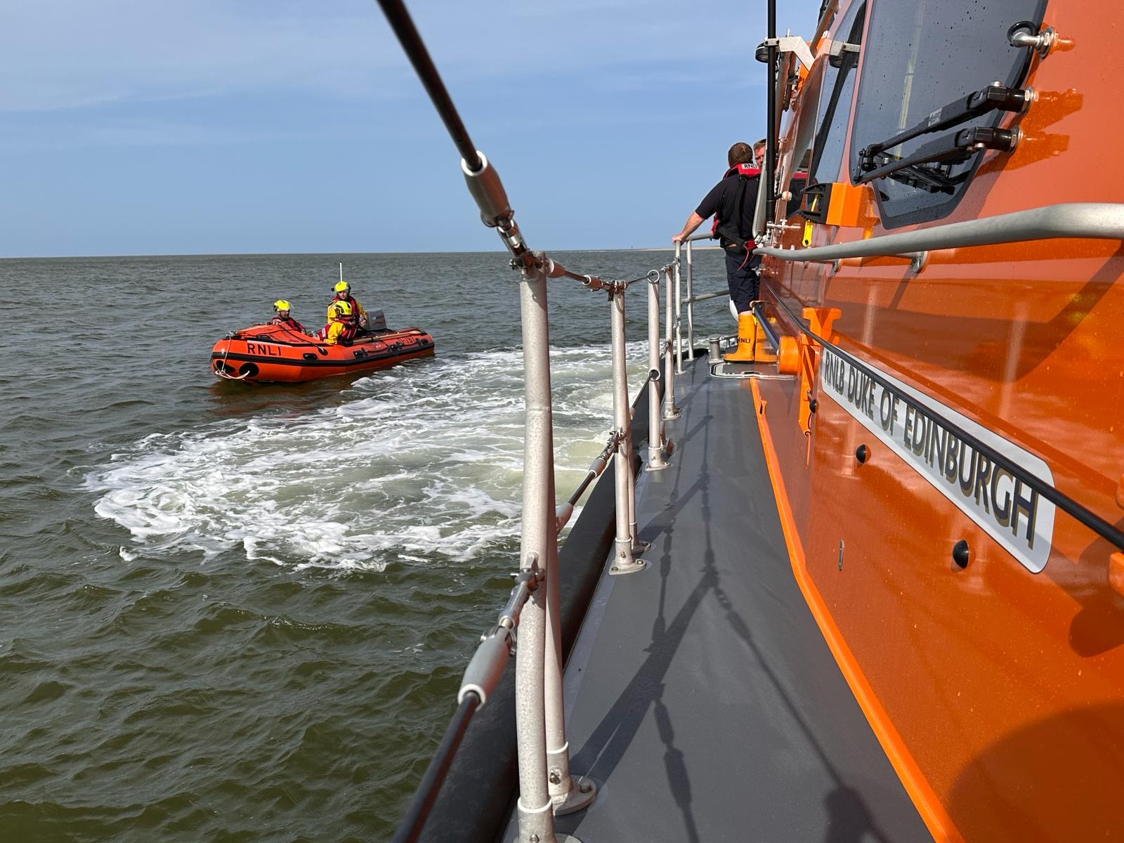 Inshore lifeboat with volunteer crew of three taken from side of Shannon class lifeboat with Duke of Edinburgh name of lifeboat showing
