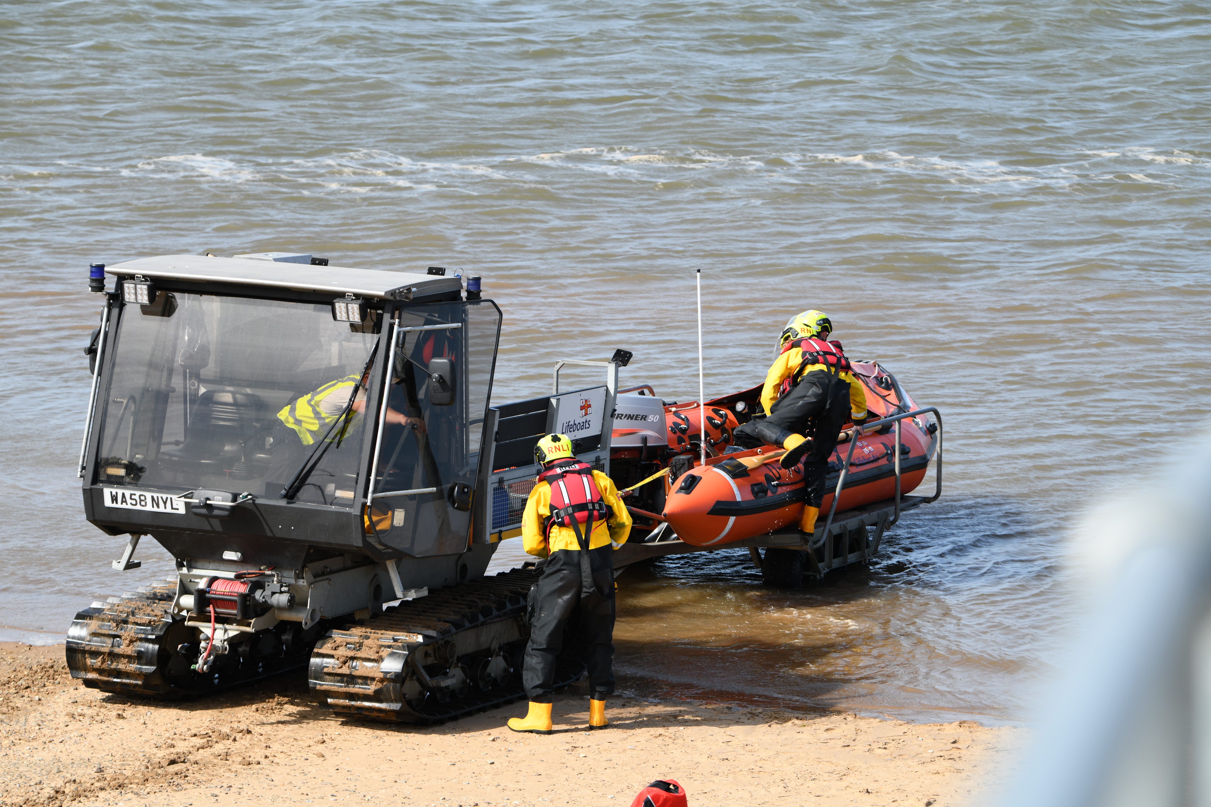 Wells RNLI volunteer crew in full RNLI kit with the inshore lifeboat and soft Trak