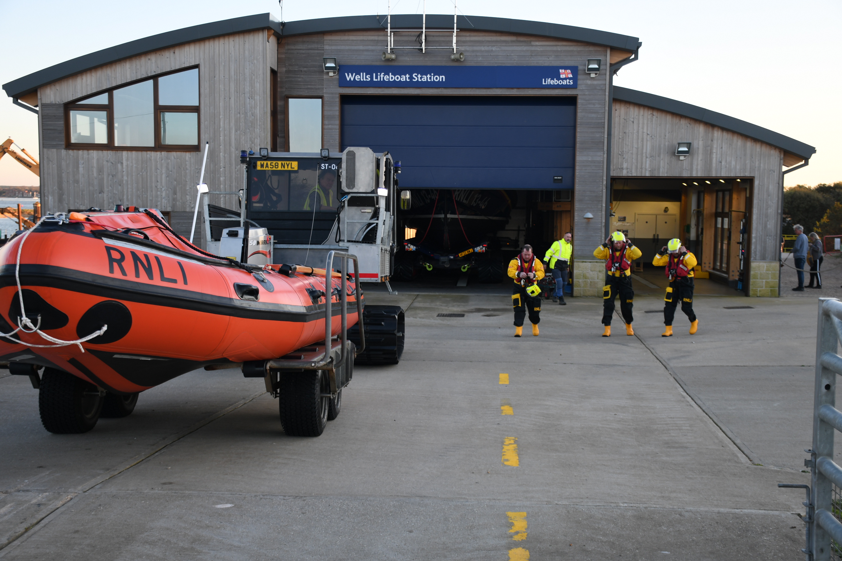 Wells RNLI lifeboat station with a crew of three in full RNLI kit on the north apron
