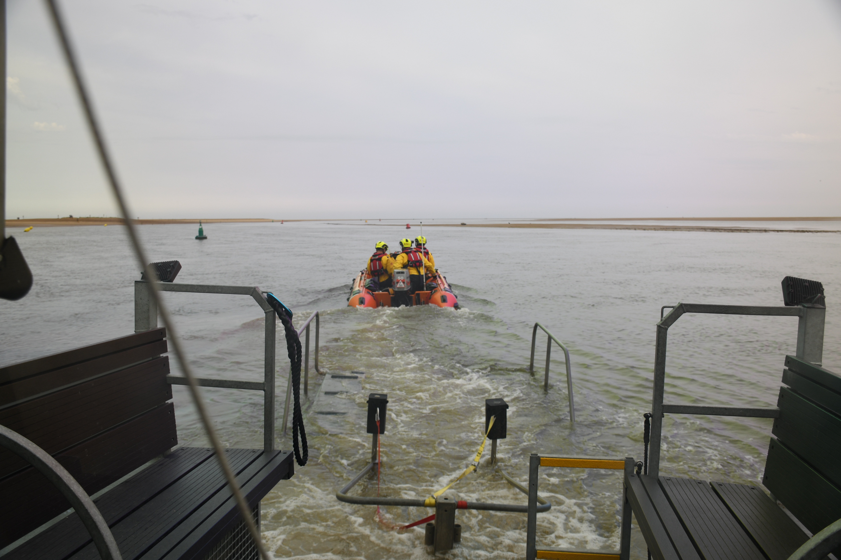 Softrak launching Inshore lifeboat with a volunteer crew of four into the water with sand bank is distance
