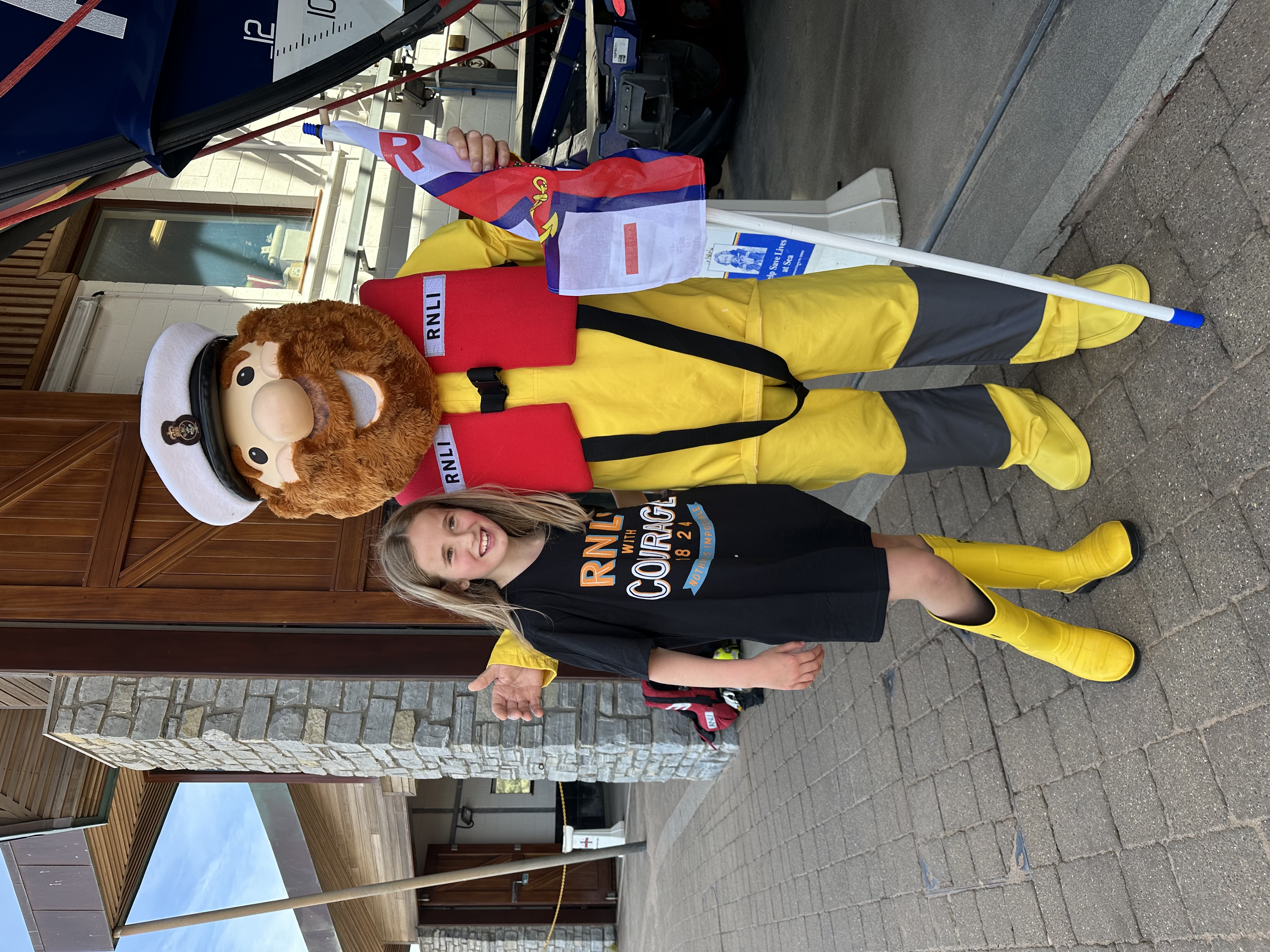 Ivie wearing iconic RNLI yellow wellies with RNLI mascot Stormy Stan