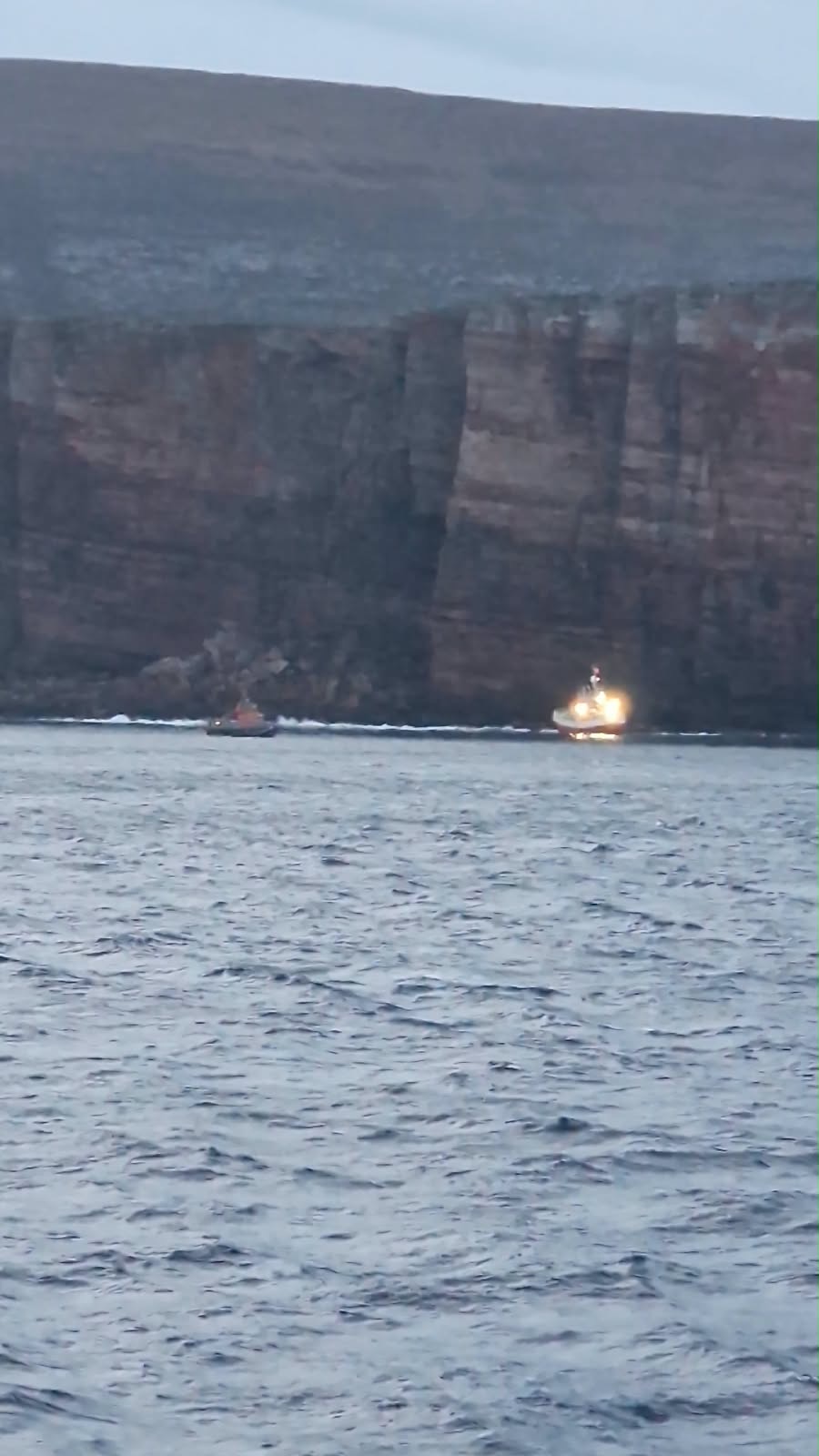 Brightly lit trawler in early morning light with lifeboat to the left