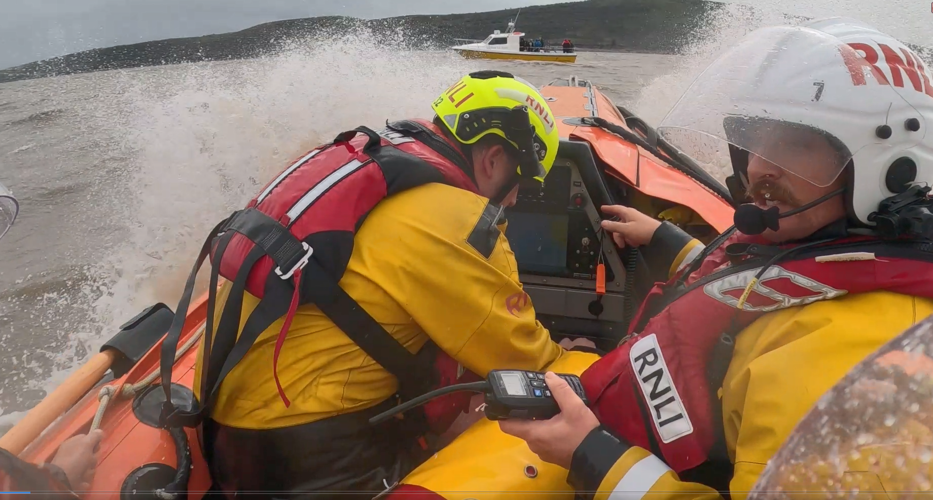 Crew members of Weston RNLI in the D Class lifeboat in Weston Bay approaching Storm Lee Charters. Water is spraying up around the lifeboat.