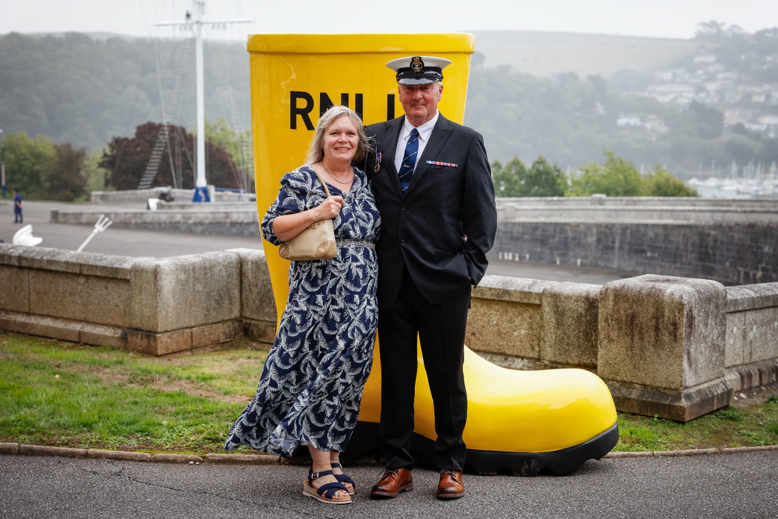 Two people standing in front of large yellow welly