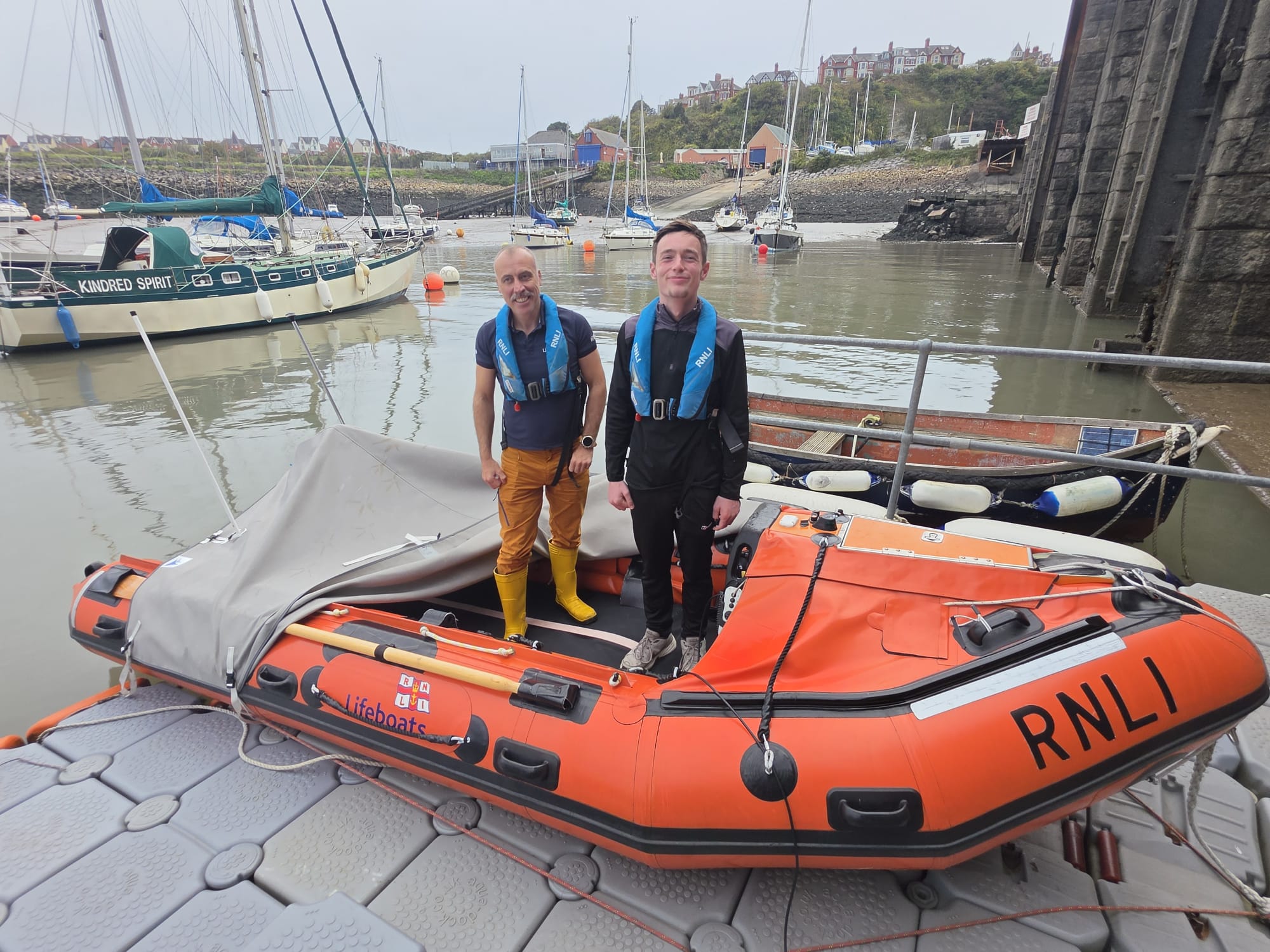 2 people standing in the orange D class inshore lifeboat smiling 