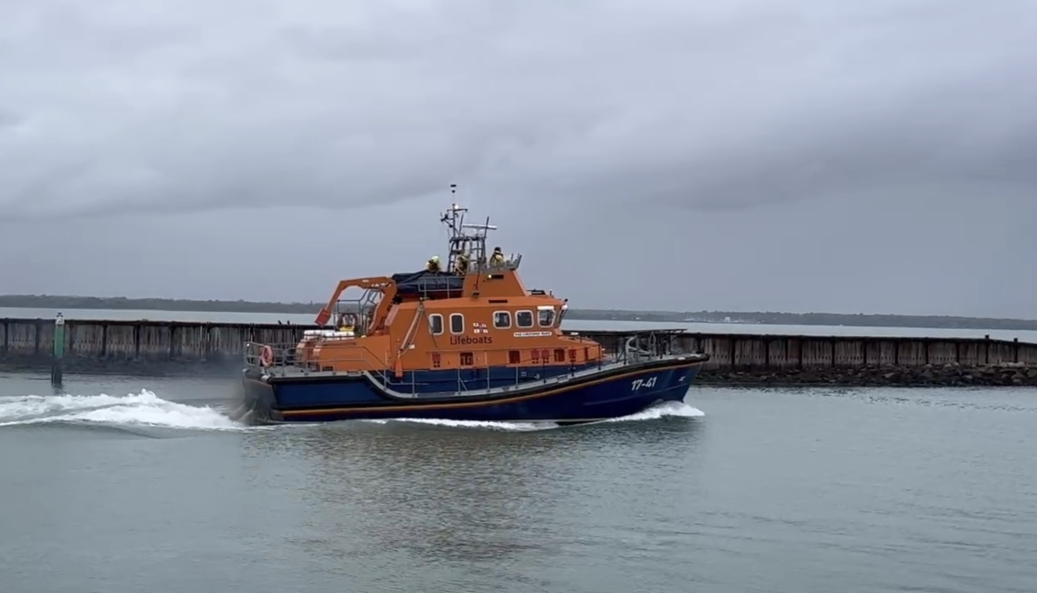 RNLI Severn class lifeboat travelling across calm harbour waters on an overcast day