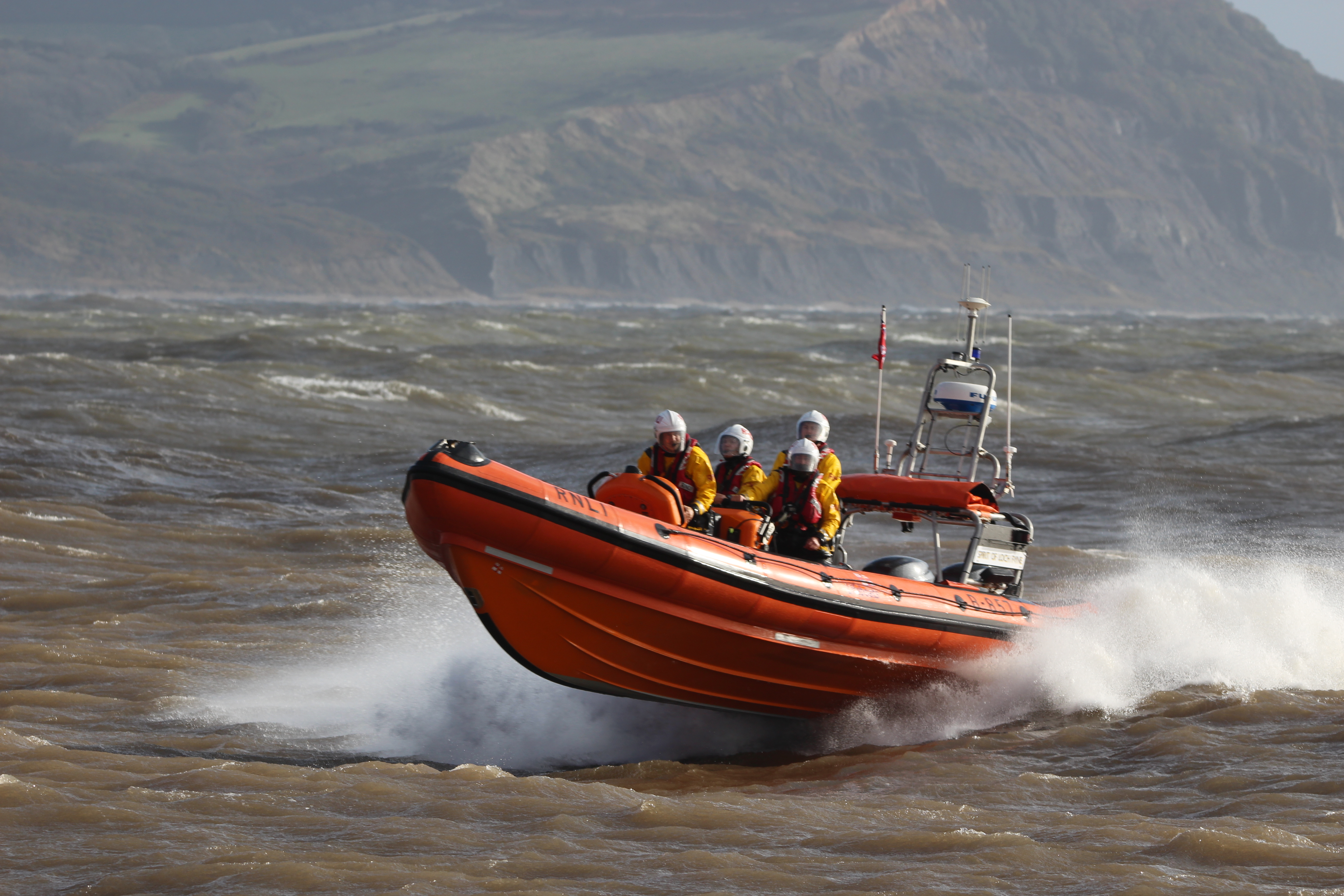 Orange lifeboat moving at speed on grey sea