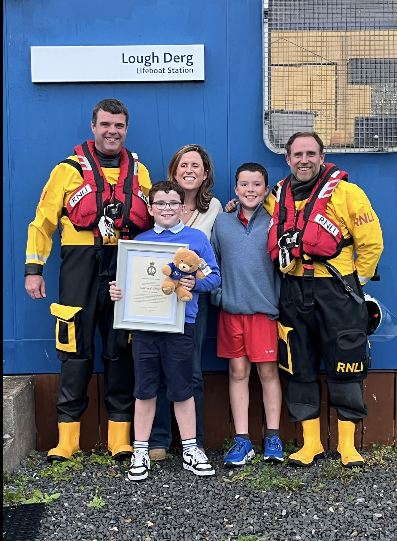 Group photograph outside the lifeboat station, Steve and Owen are in full kit, Darragh is proudly holding his RNLI Certificate of Thanks