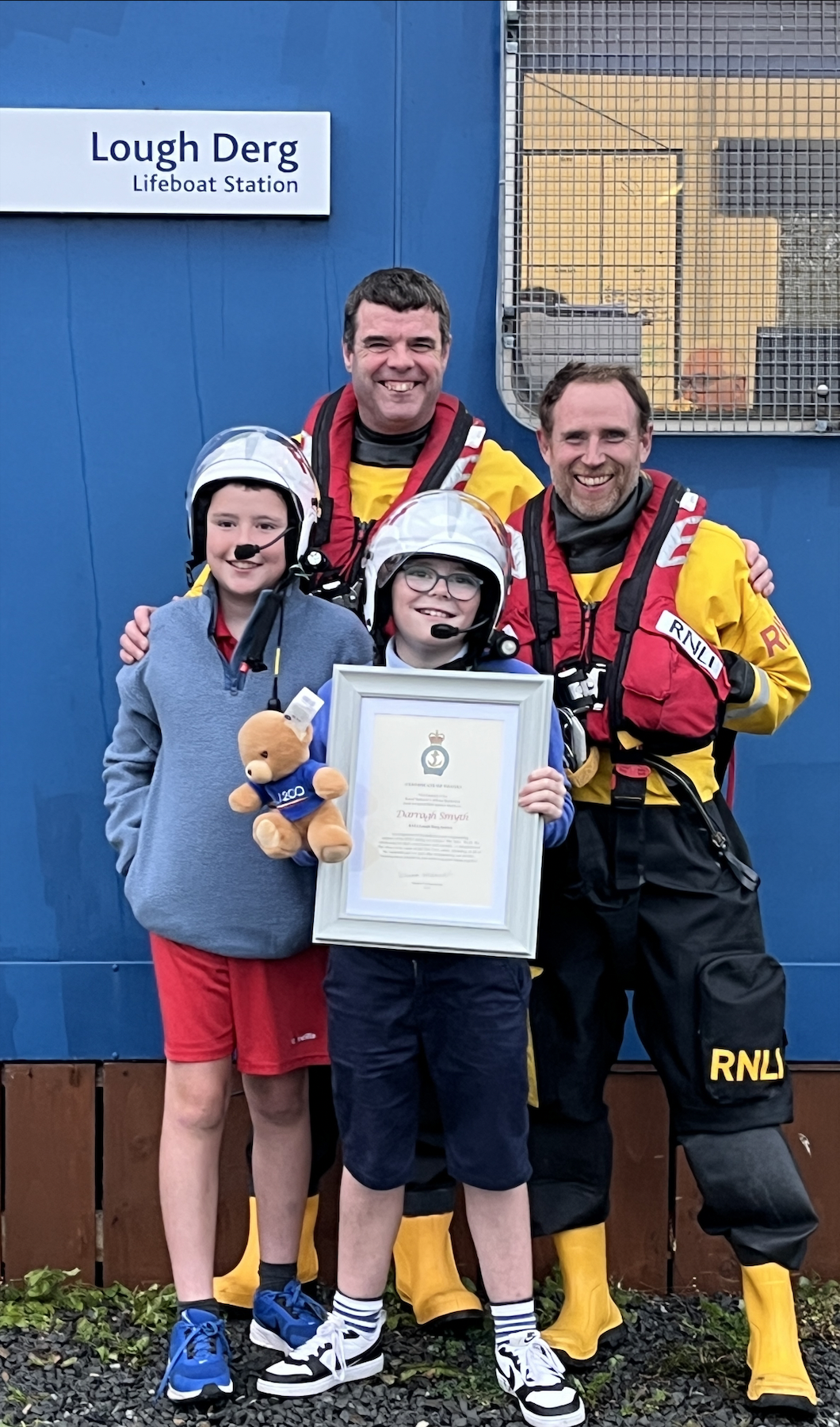 Cathal and his brother Darragh standing with Steve, their Dad, and Owen, their uncle, outside Lough Derg RNLI Lifeboat Station