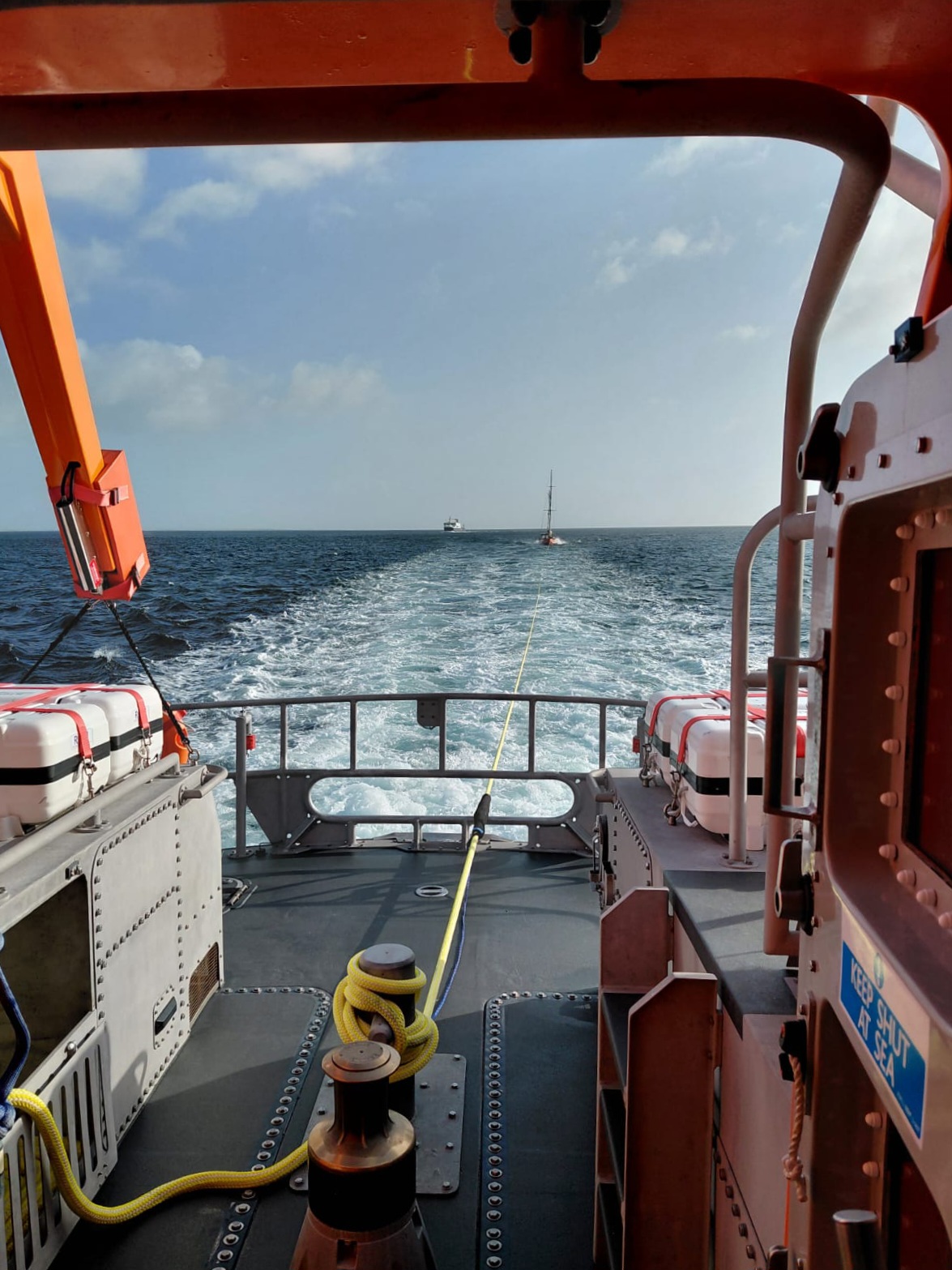 View out along the back deck of the lifeboat with a yacht on tow and a north isles ferry approaching in the distance.