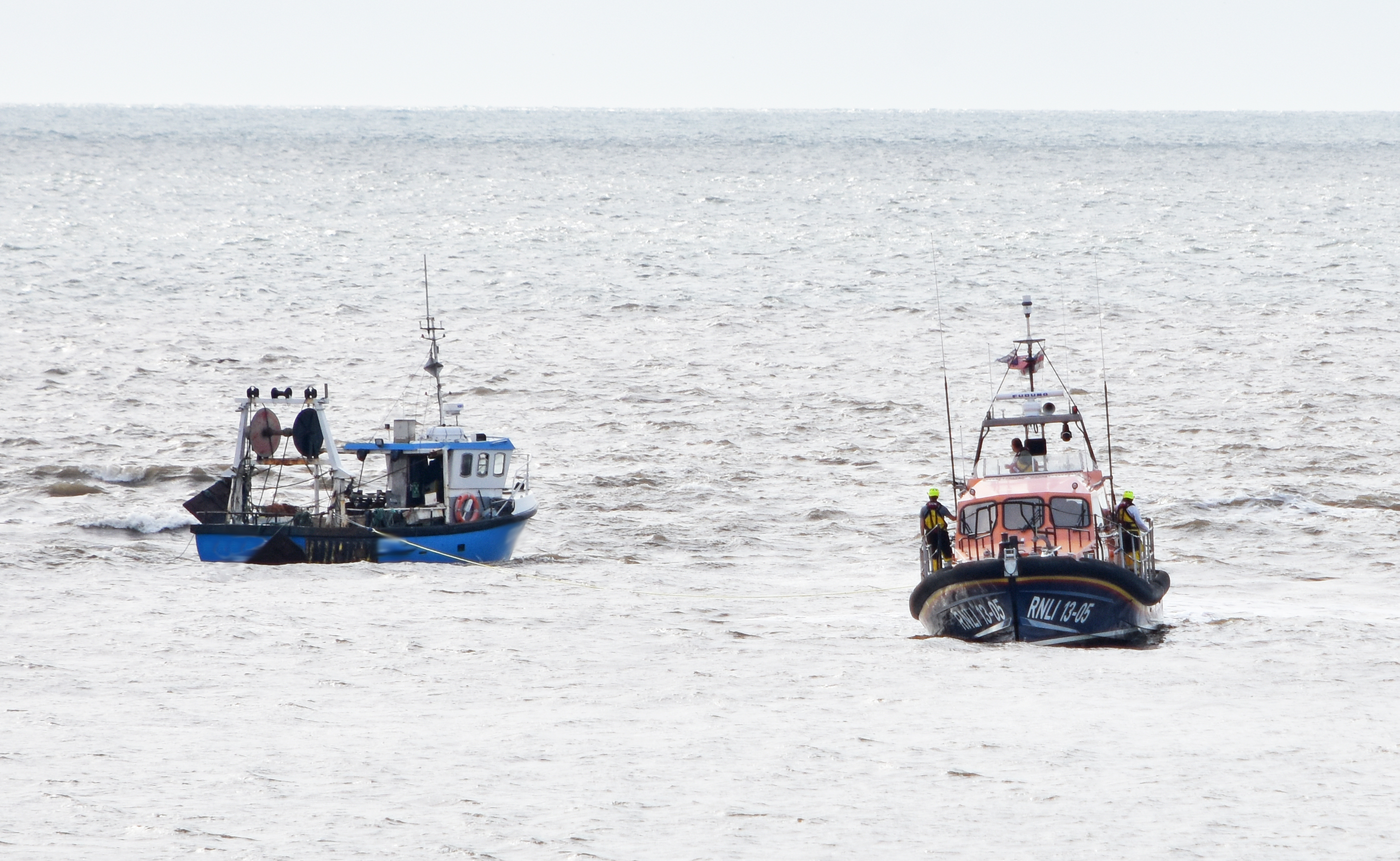 Lowestoft RNLI lifeboat stands by the grounded fishing vessel as the tide rises