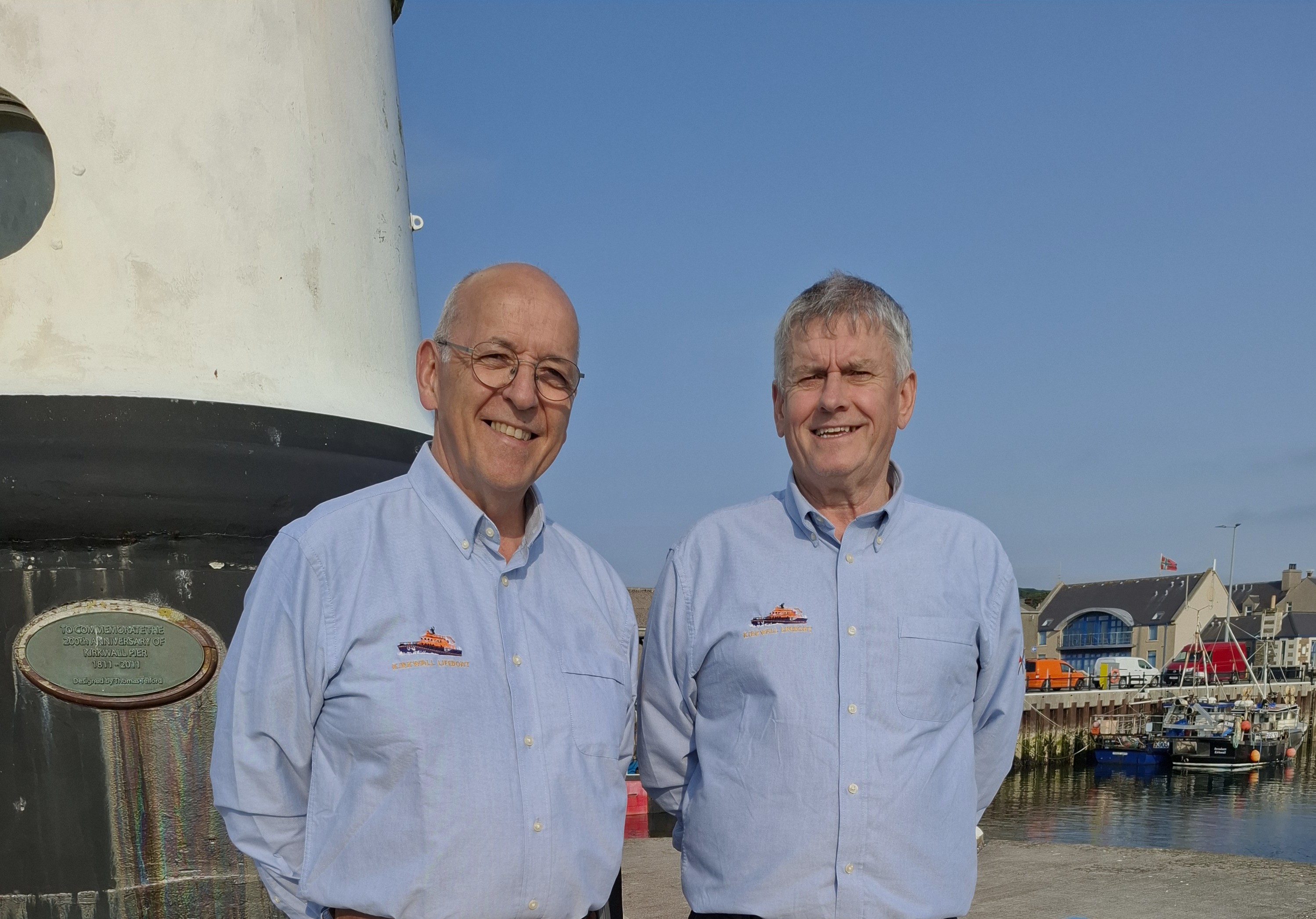 Chris Irvine and Brian Kynoch sstanding at the foot of the small lighthouse at the end of West Pier Kirkwall.