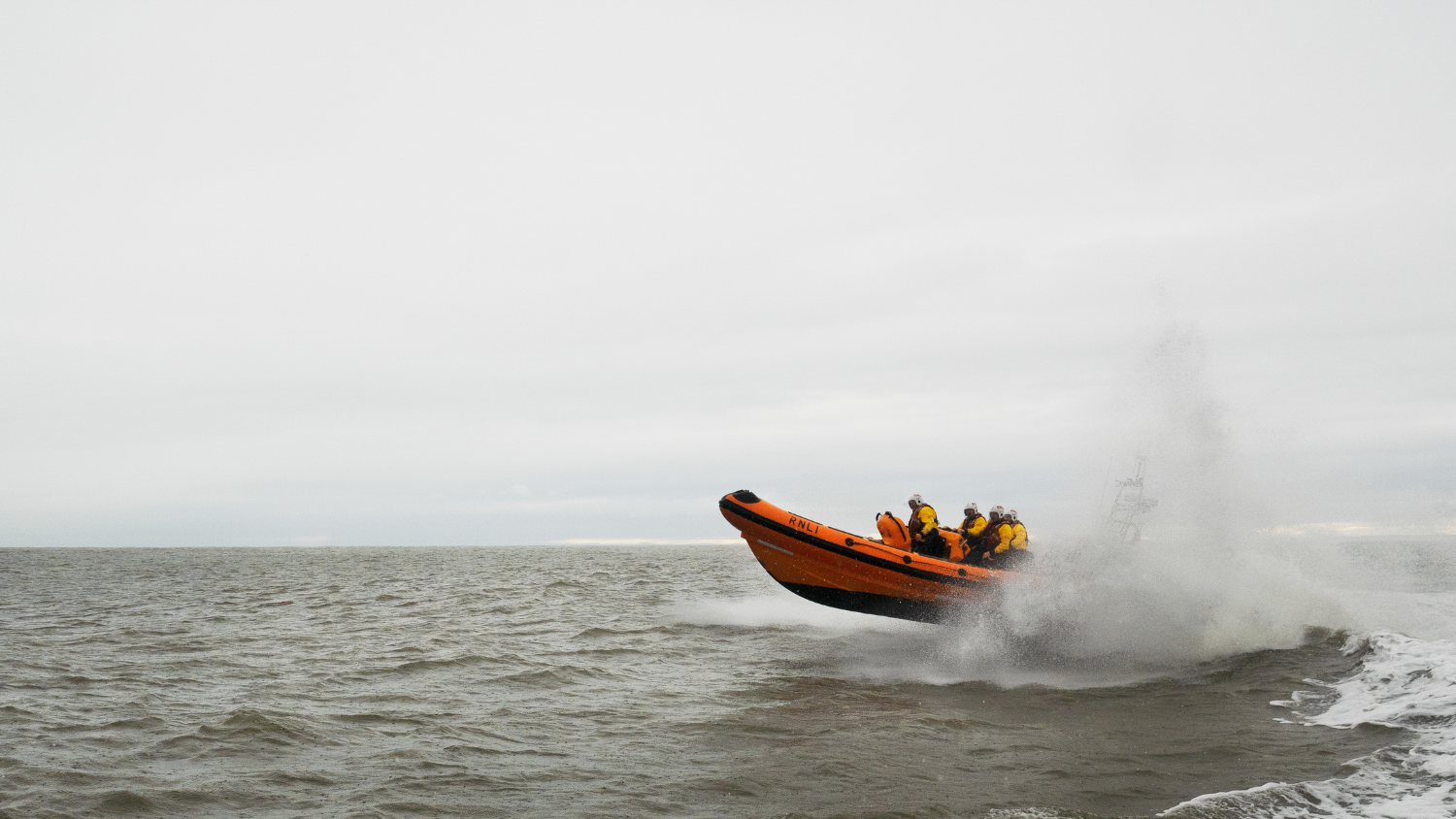 Arbroath Atlantic 85 inshore lifeboat Dylan Rotchell B-927 at sea during a training exercise. Crashing through a breaking wave, lots of white spray.