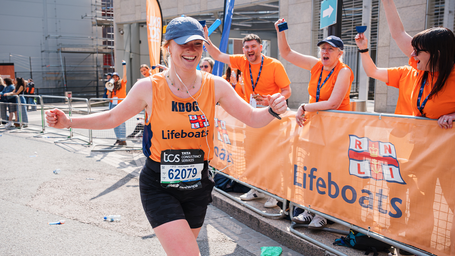 A woman runs the London Marathon in support of the RNLI with people are cheering her on.
