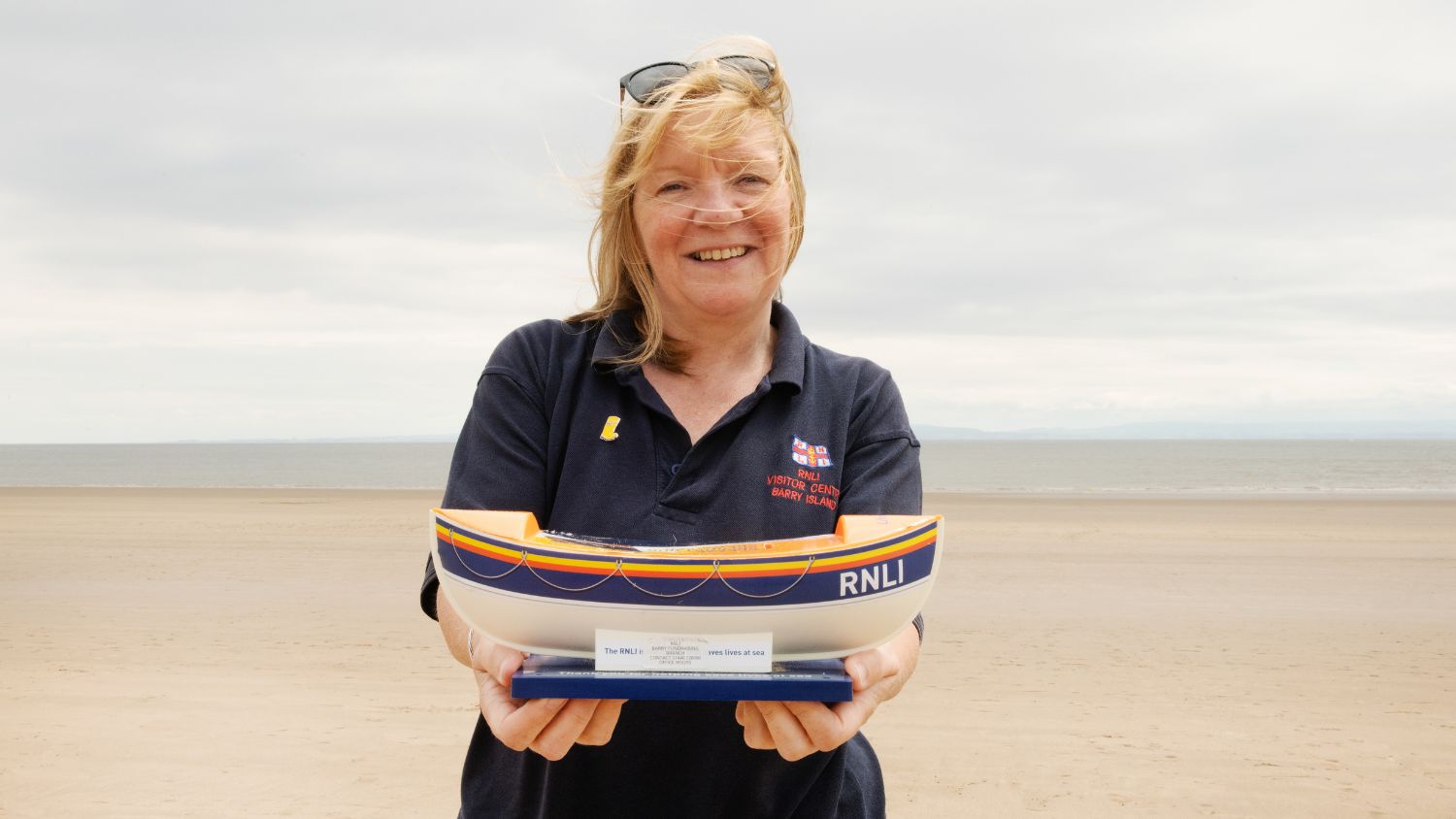 ortrait of Barry Island shop retail volunteer Rosemary Fisher holding lifeboat  collecting bucket.