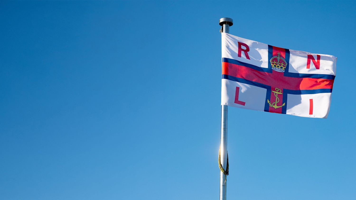 RNLI flag against a blue sky.