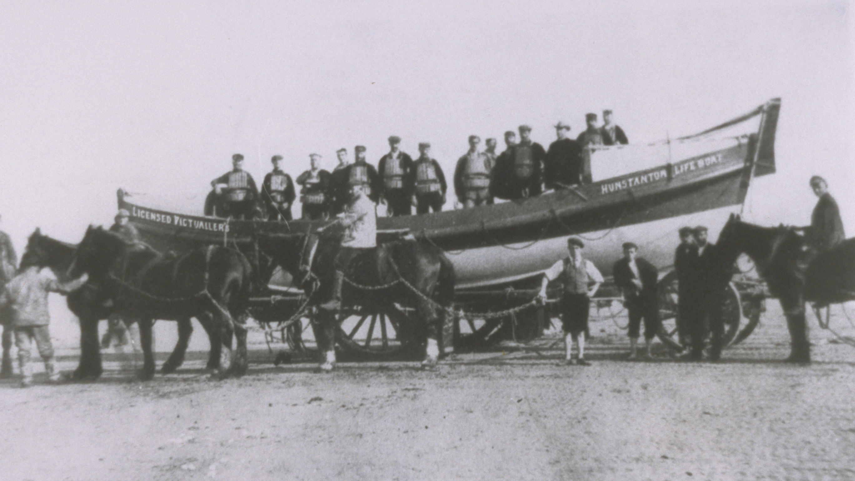 Hunstanton crew onboard their Self Righting class lifeboat, Licensed Victualler, as she sits on her horse-drawn carriage on the beach. Circa 1900-1931.