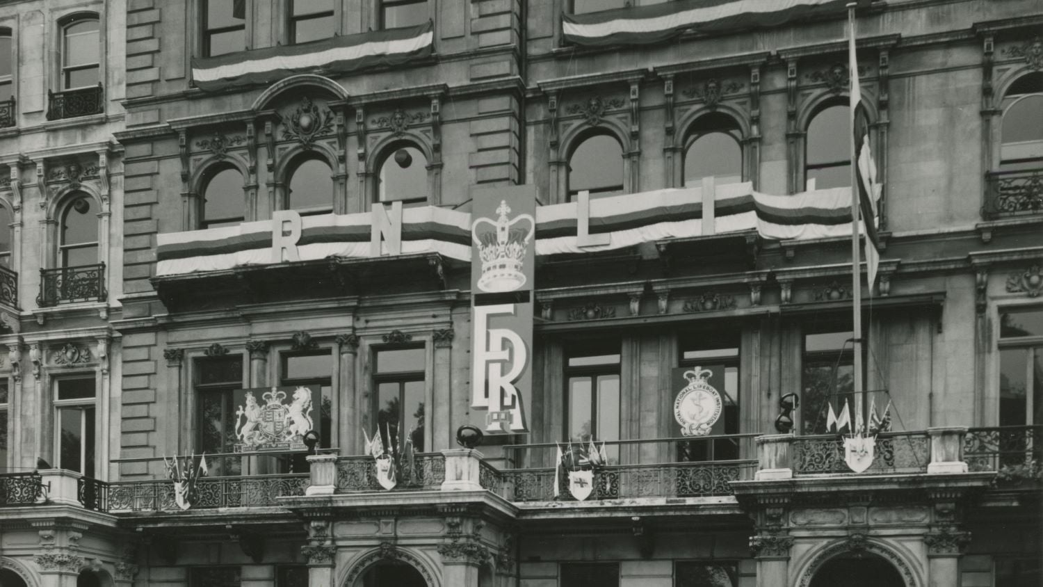 Black and white image of exterior of RNLI Head Office with coronation banner and flags