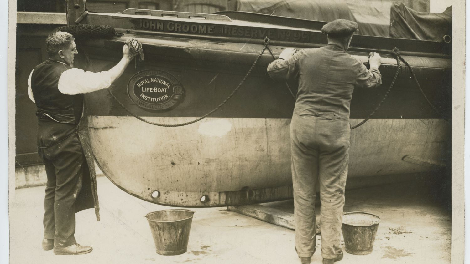 Black and white image of workmen cleaning lifeboat