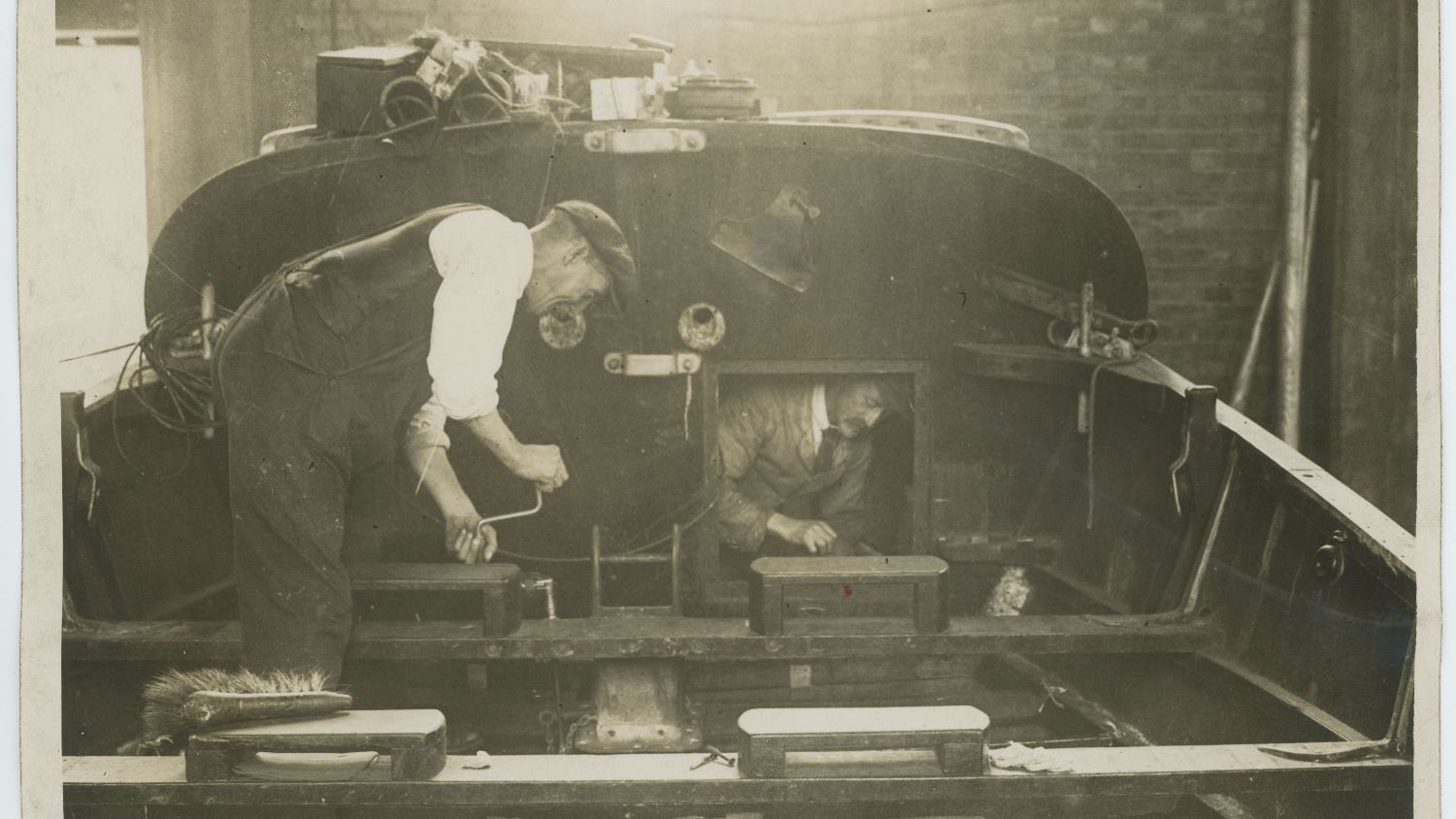 Black and white image of two men working on deck of lifeboat