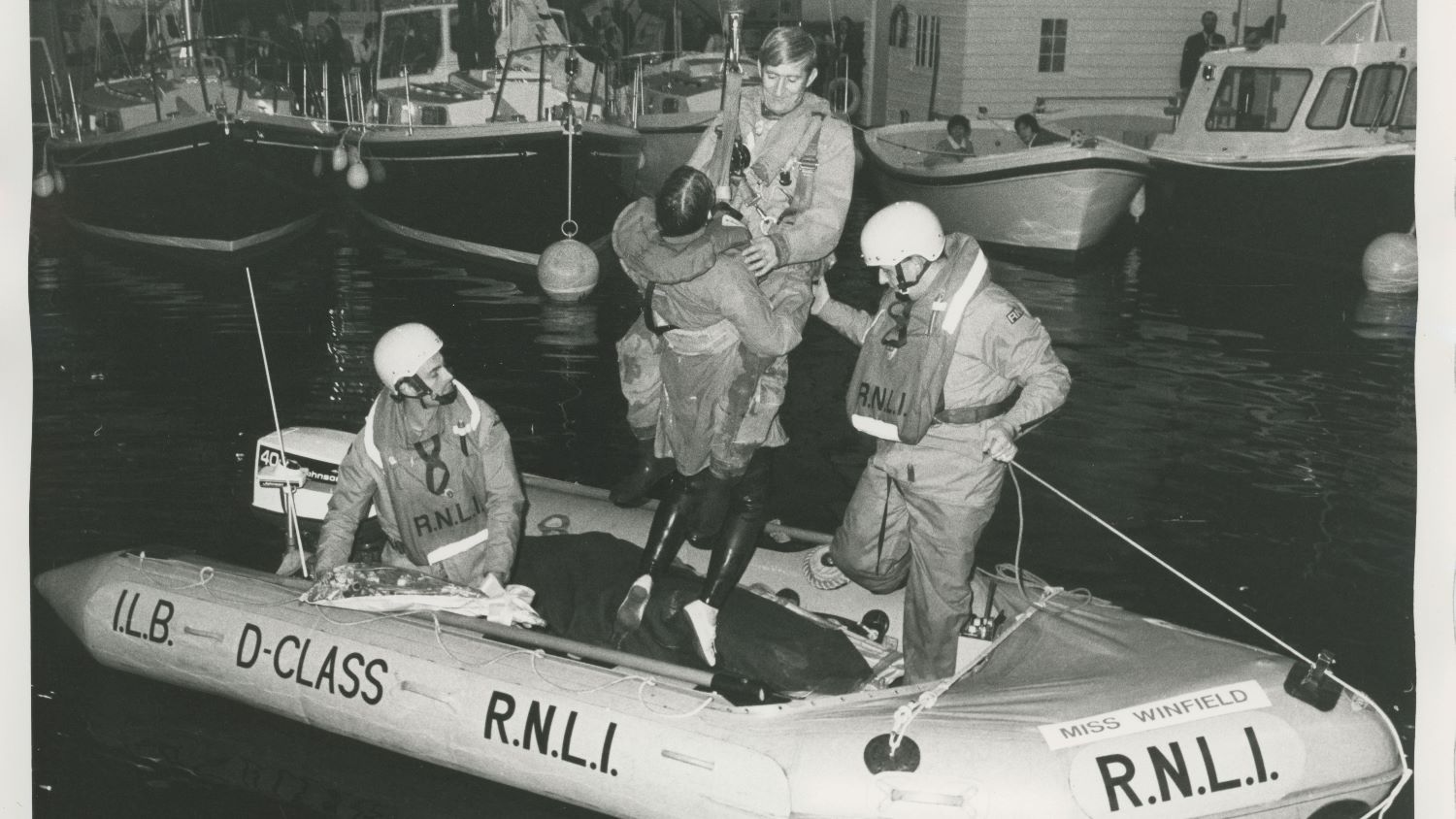 Black and white image of crew member being lifted from inshore lifeboat