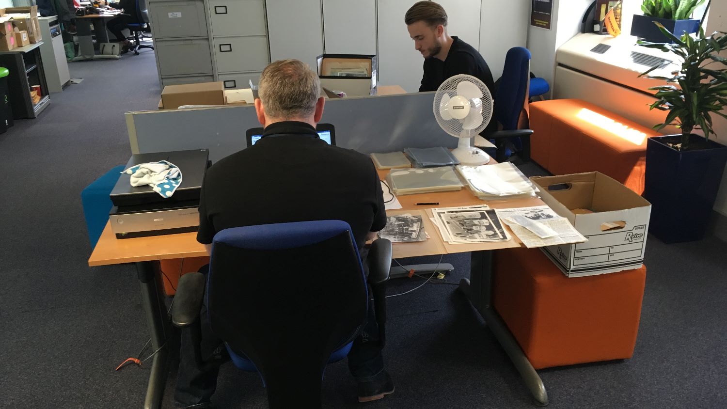 Colour image of two student volunteers cataloguing and digitising photographs 