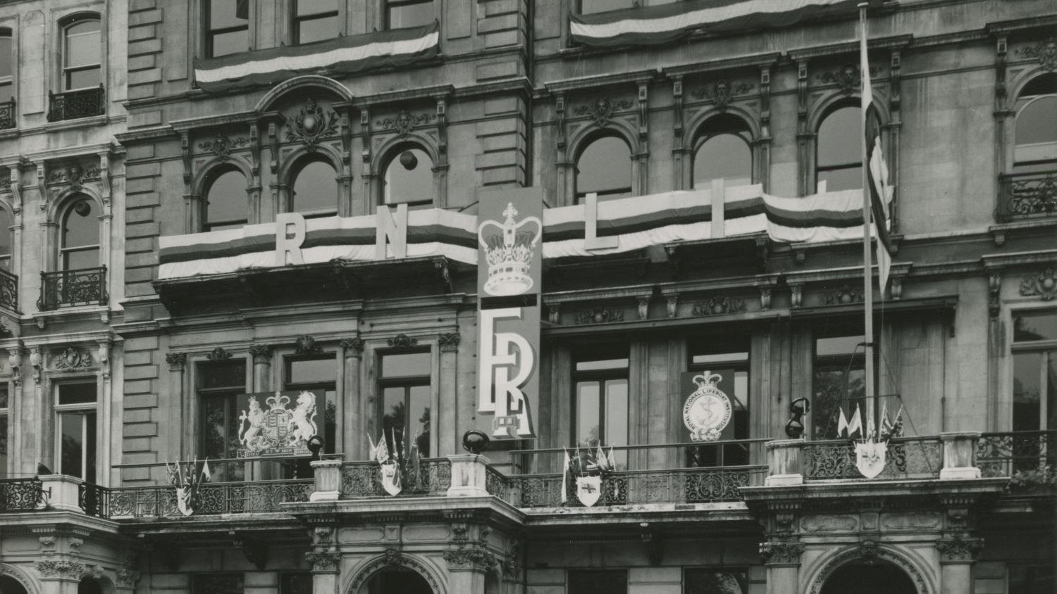 Black and white image of exterior of RNLI Head Office with coronation banner and flags