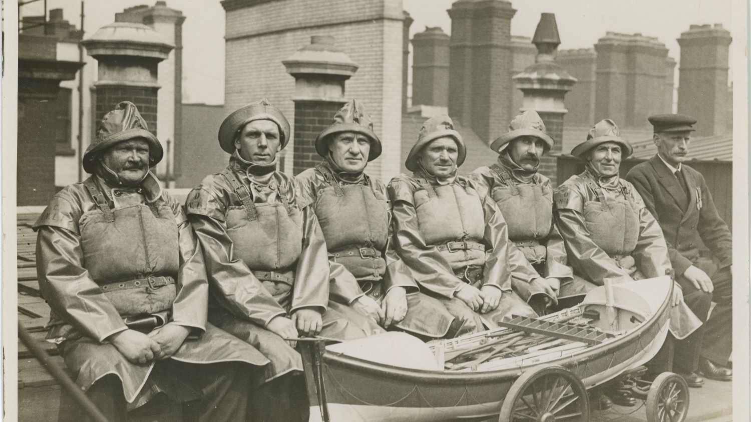 Black and white image of seven men in crew kit with medals