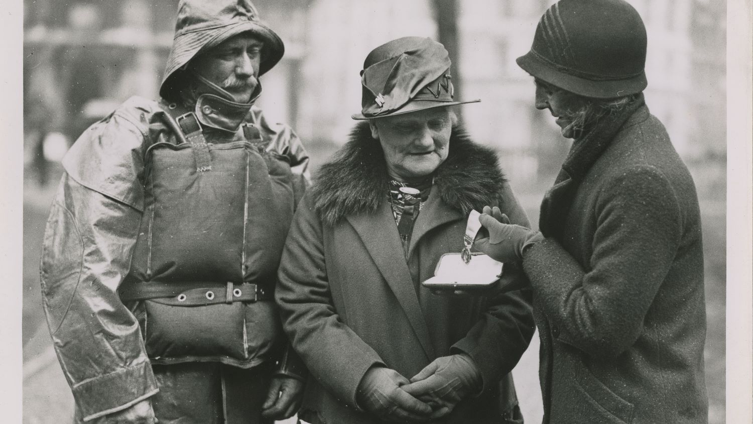 Black and white image of two women and one man with medals