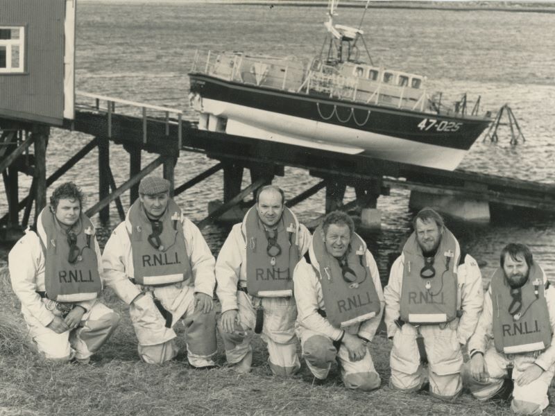 Black and white image of six crew members with lifeboat on slipway