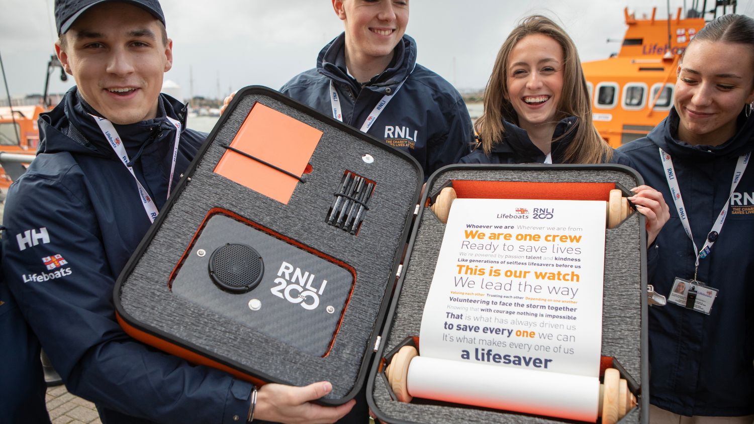 RNLI Face to Face team holding the RNLI 200 scroll and case