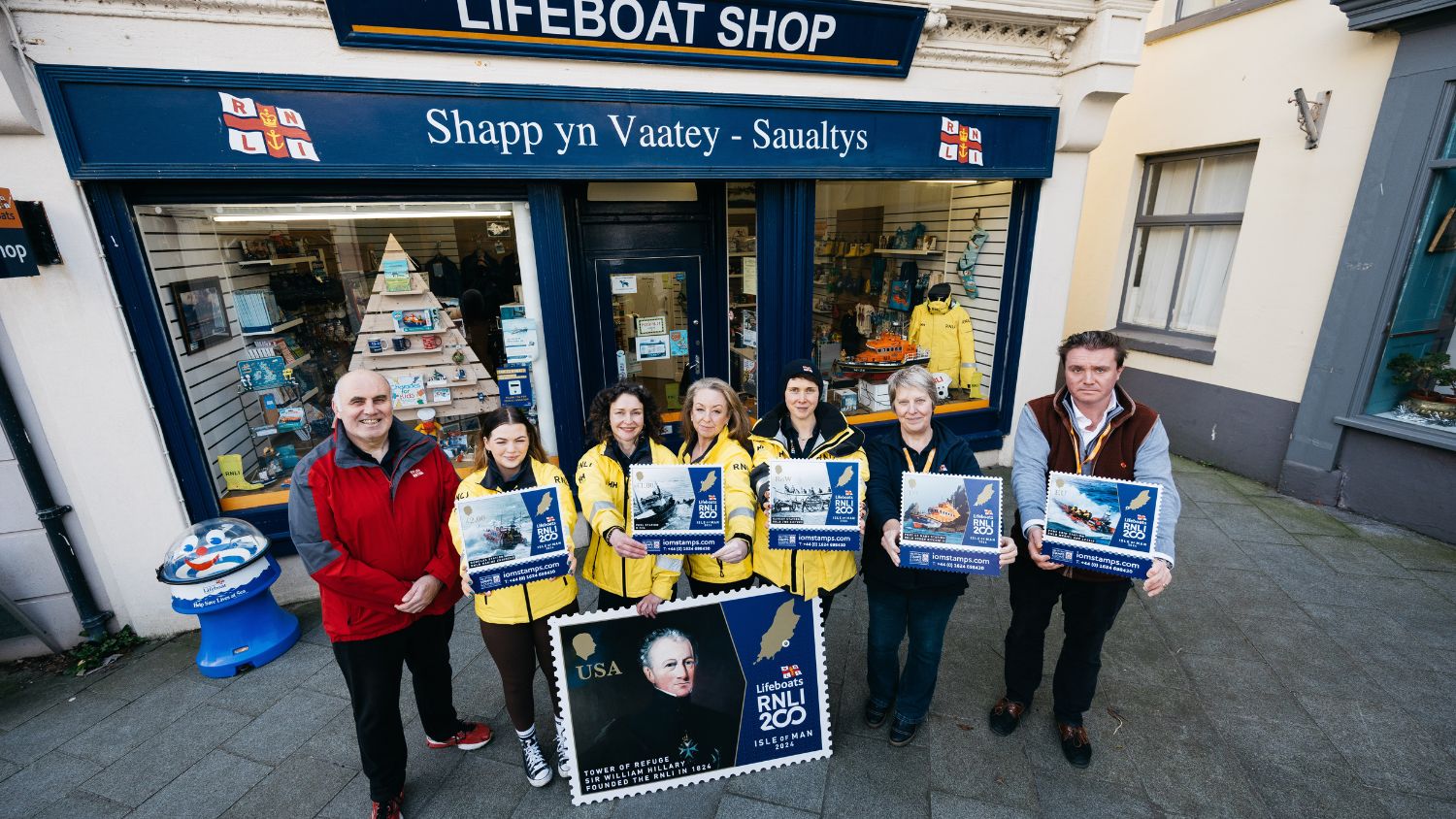 Volunteers outside RNLI Ramsey Shop holding the new Isle of Man post Office stamps for RNLI 200 Anniversary