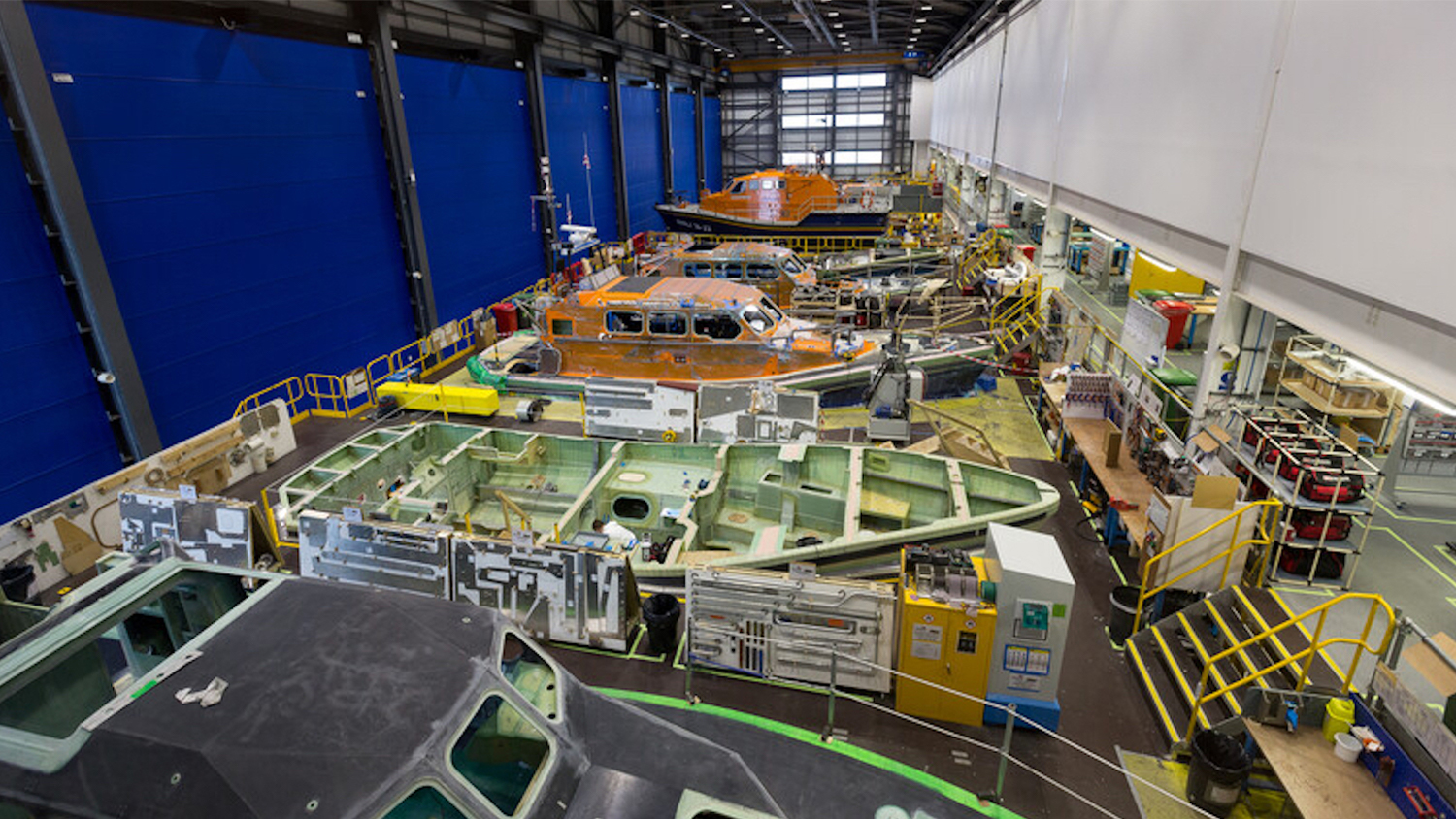A scene from the inside of the RNLI’s All-weather Lifeboat Centre in Poole, Dorset. This is where all-weather lifeboats are designed, built, repaired and maintained. The scene shows all-weather lifeboats within the vast building, at various stages of the build process. 