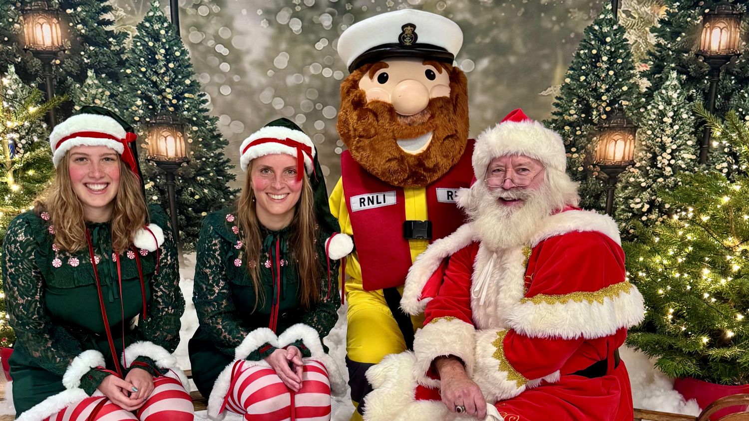 Santa posing with Stormy Sam and two elves in front of festive background
