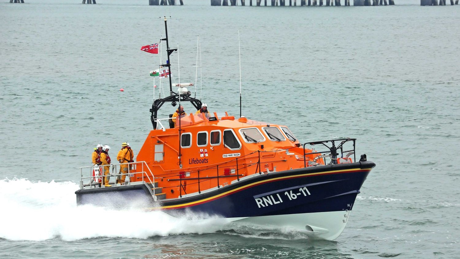 A Tamar all weather lifeboat powers over the water creating a white wake.