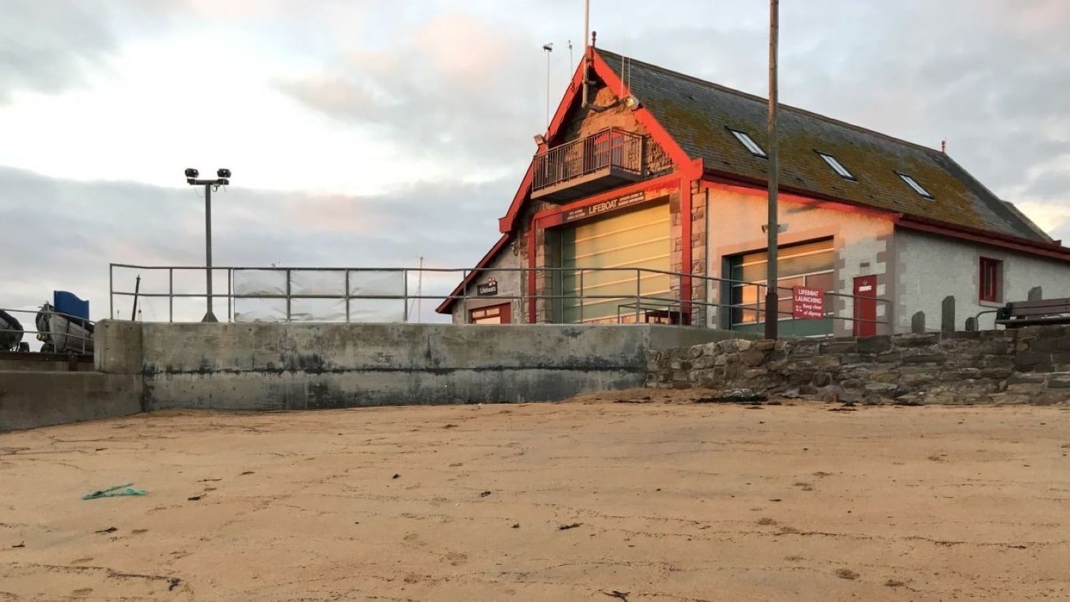 A two-storey building with pointy roof and large boatshed doors.