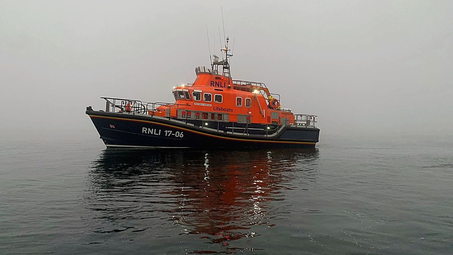 A Severn class all weather lifeboat sat on calm water in the mist.