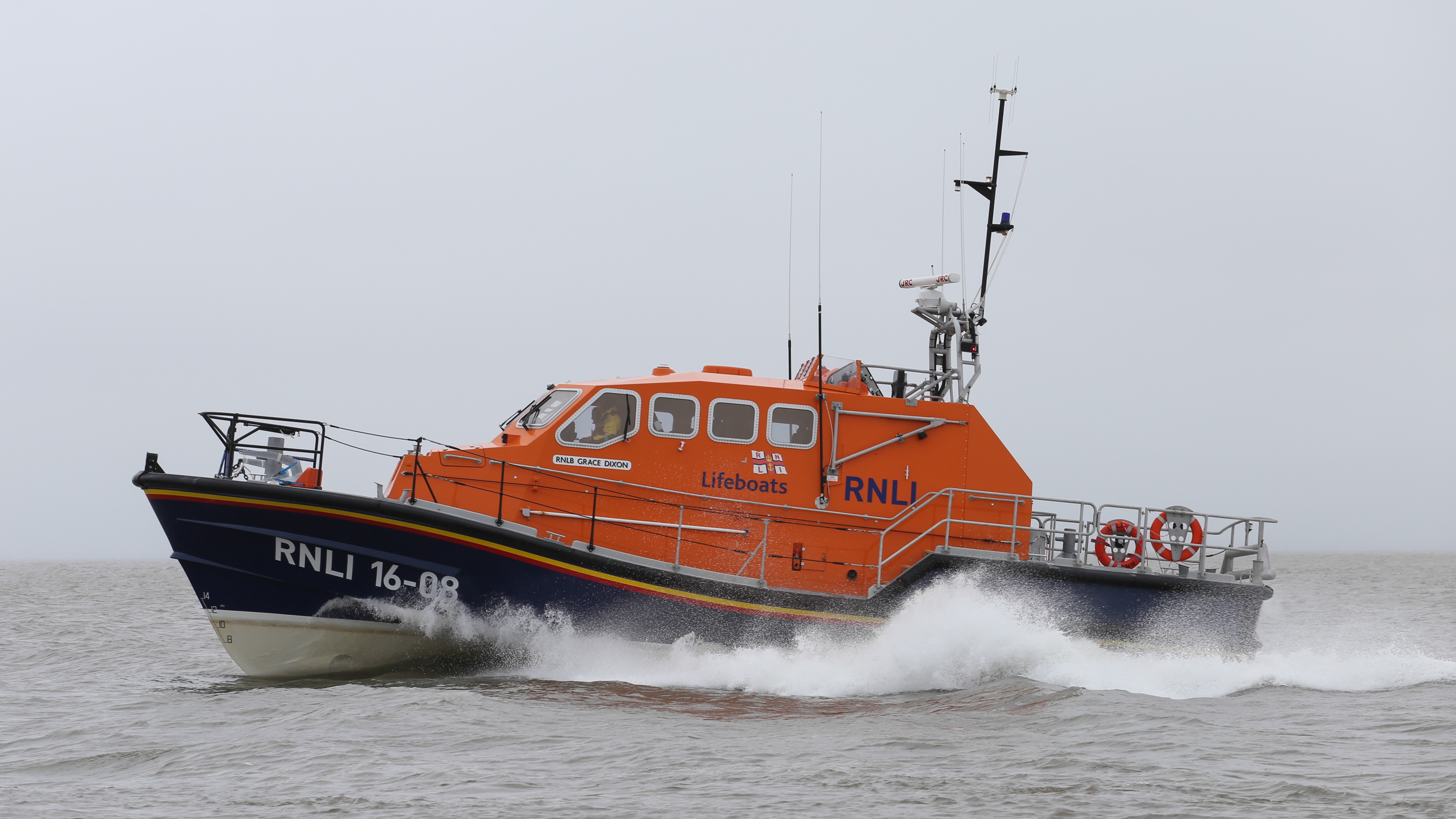 RNLI lifeboat moving quickly across the sea, creating a spray of water.