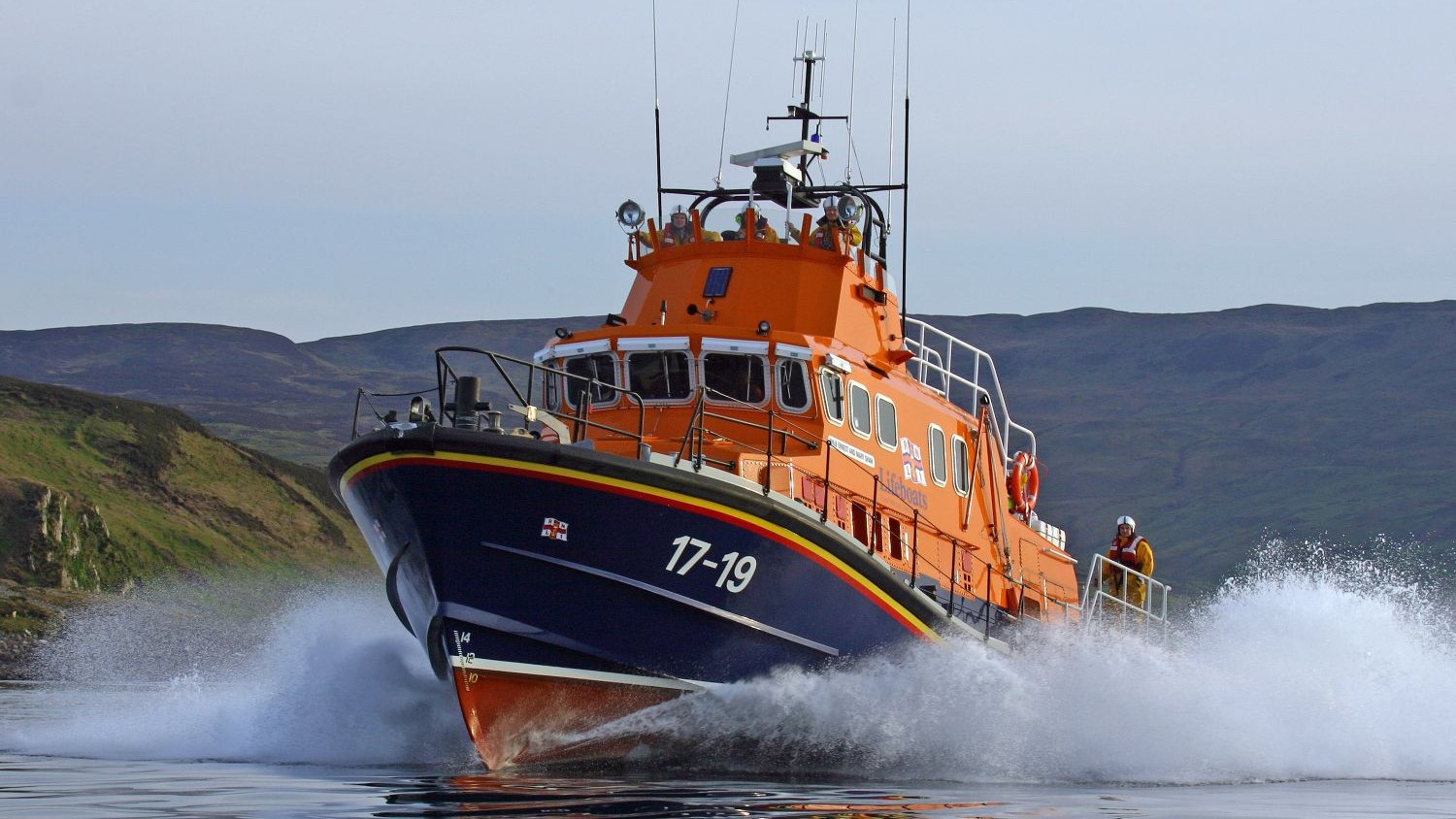 A Severn class all weather lifeboat on calm water creating spray.