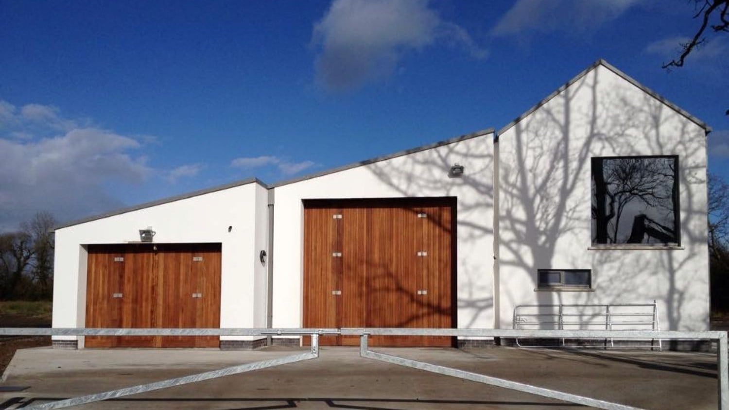 Two white building with sloping rooves and large wooden boathouse doors.