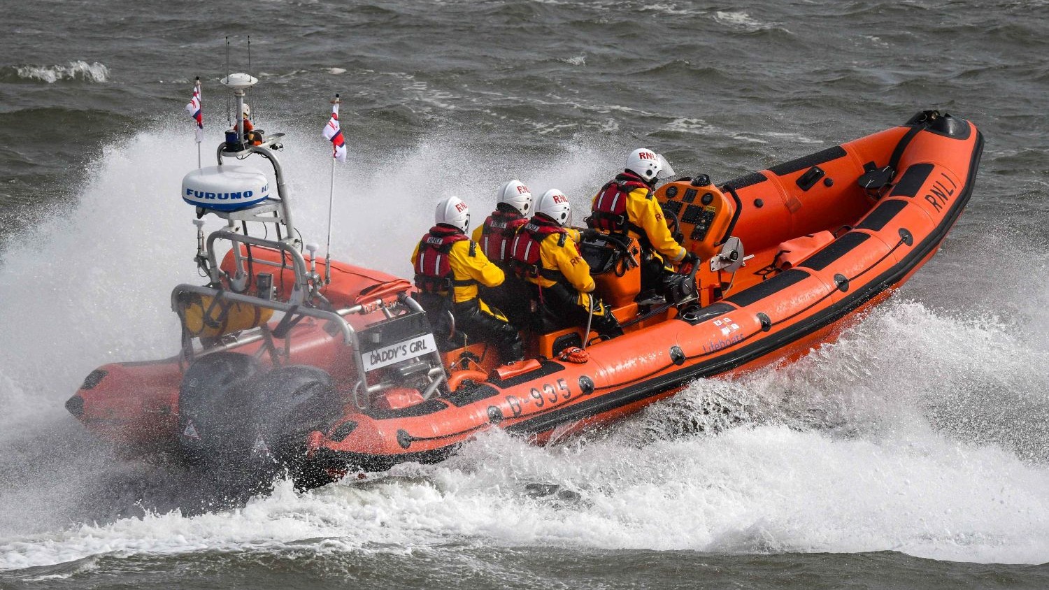 A large rib with four crew in choppy grey waves.