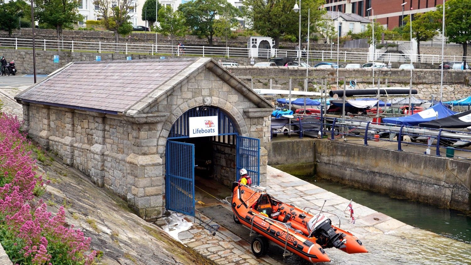 A small stone boathouse with blue gates to a slipway.