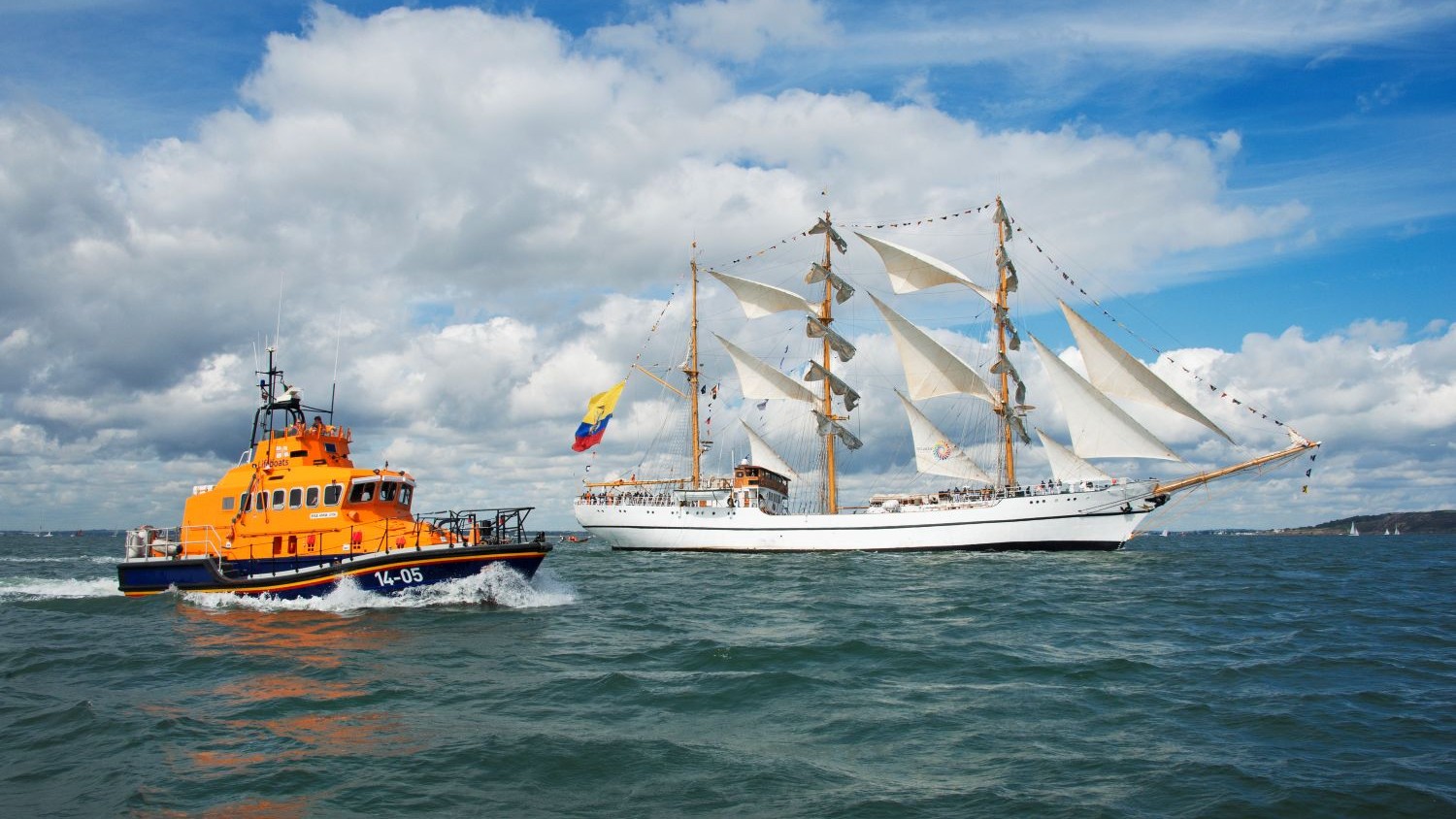 A Trent class all weather lifeboat beside a tall ship.