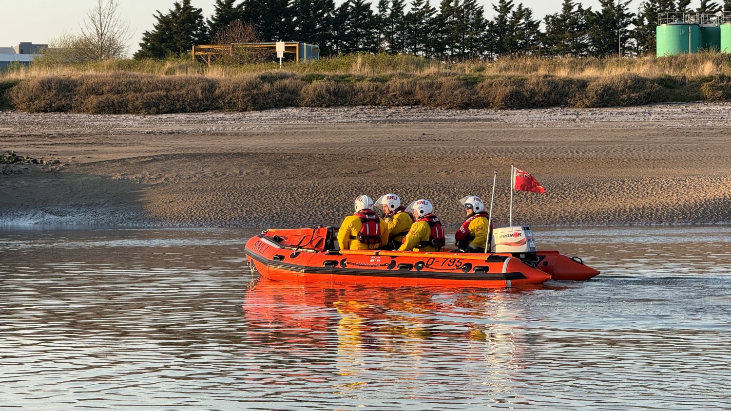 A small rib on calm water with four crew onboard.