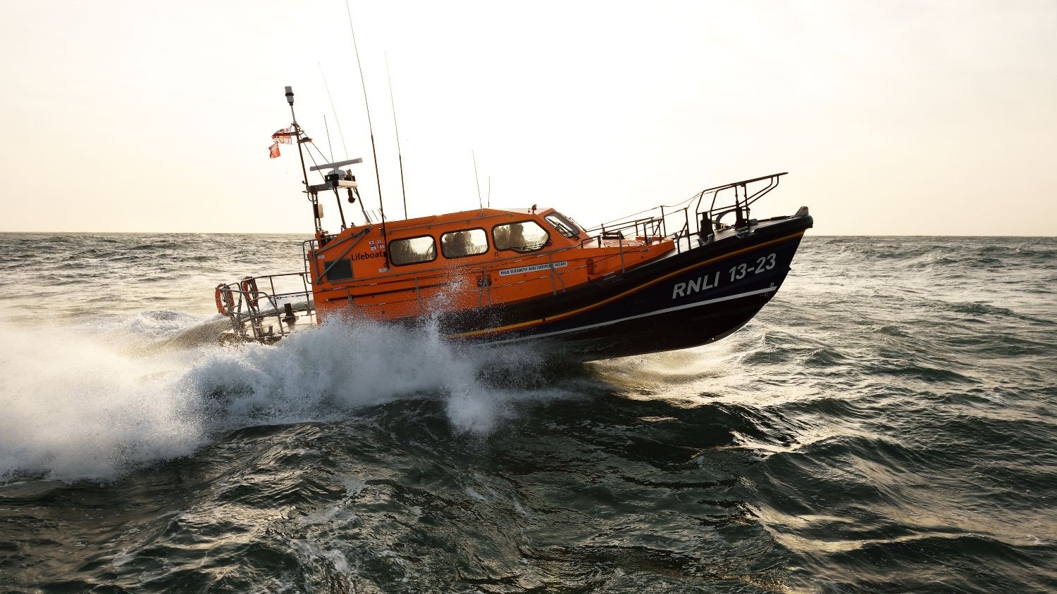 A Shannon class lifeboat crests a wave creating spray.