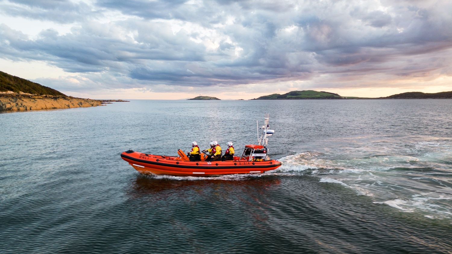 The Kirkcudbright lifeboat on calm water with a dramatic sky.