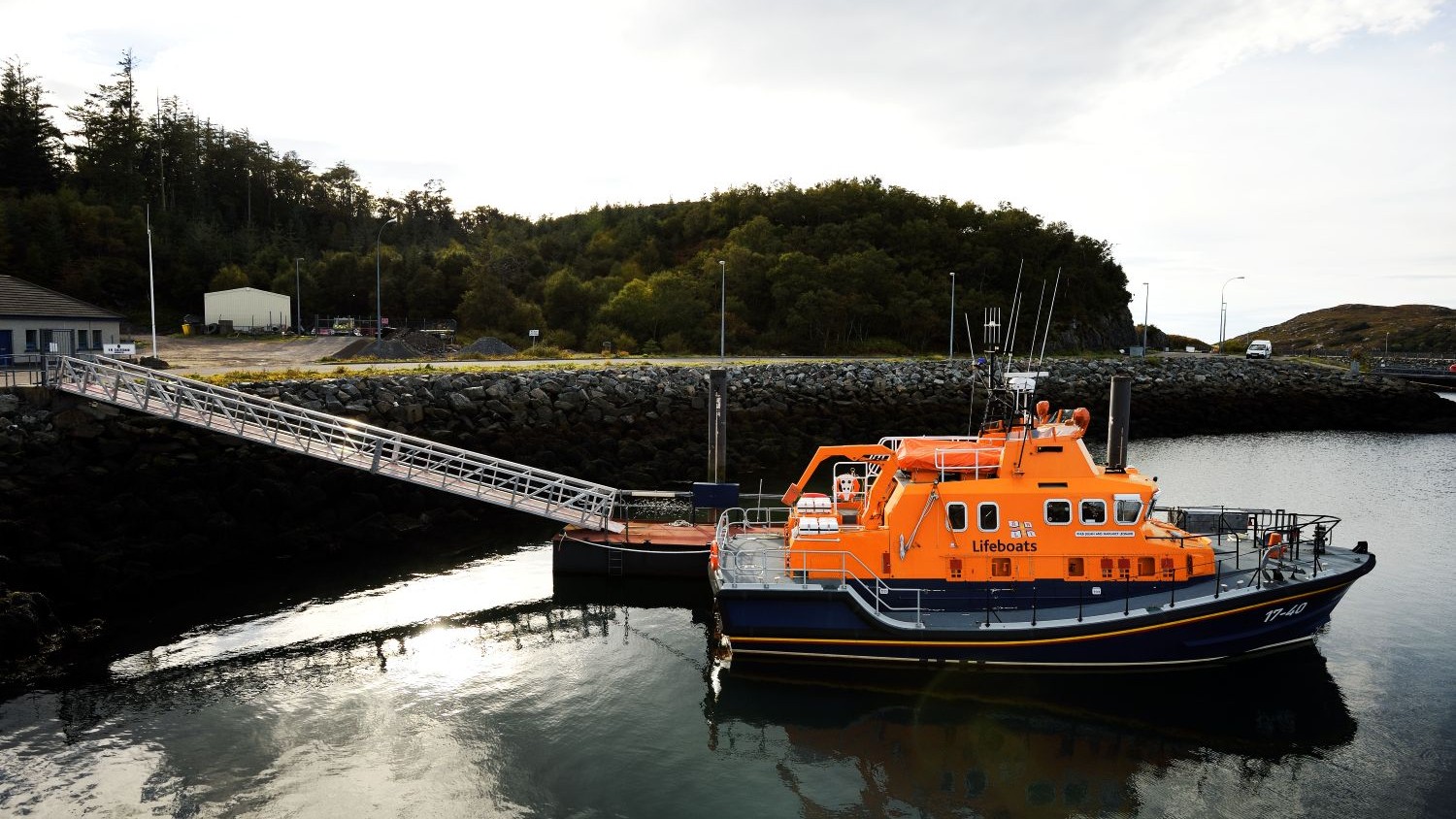 A Severn class all weather lifeboat moored at a pontoon in calm water.
