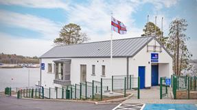 Lough Ree Lifeboat station, a modern, white, two-story building with a gray pitched roof sits by a body of water under a partly cloudy sky.