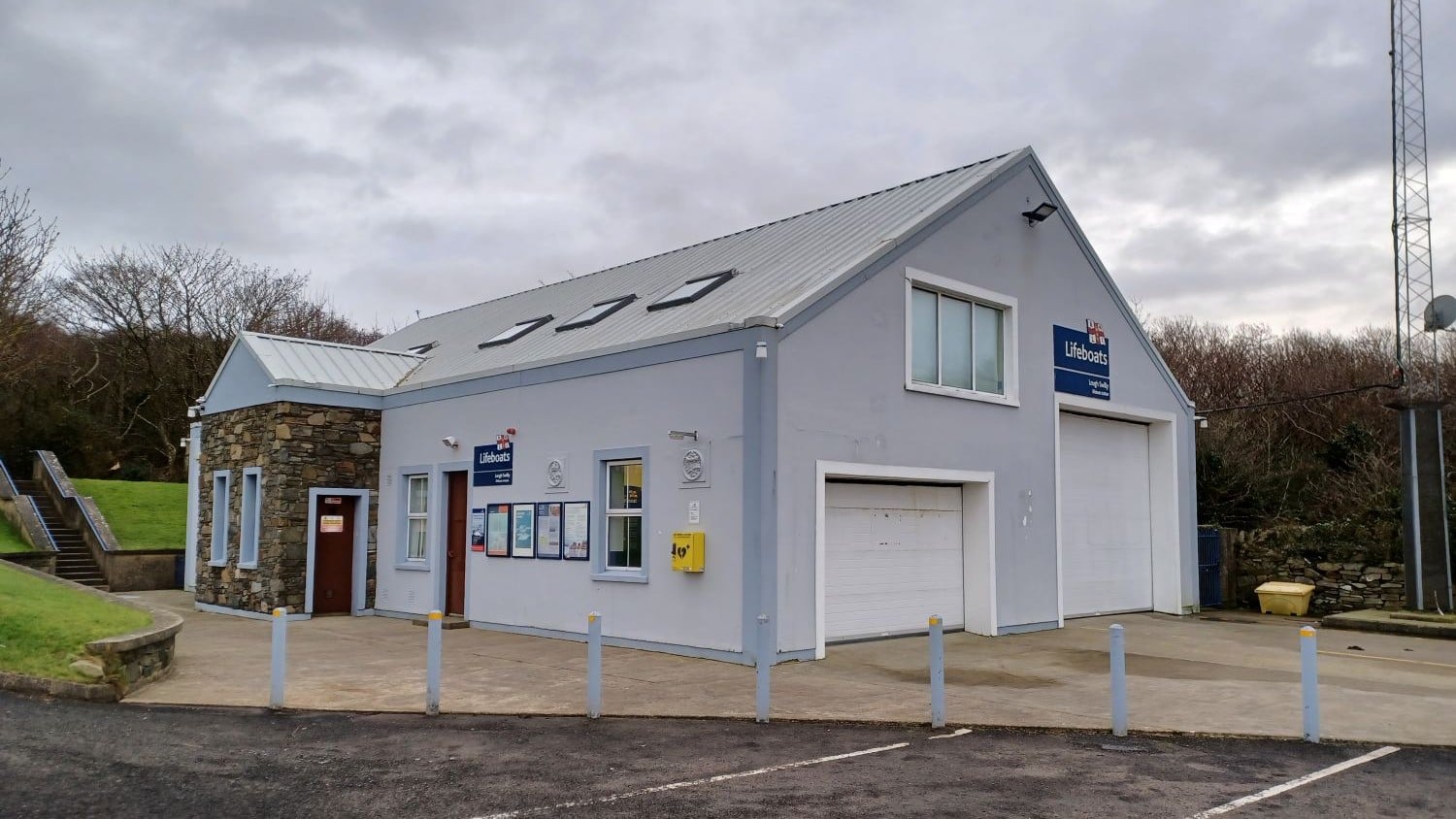 Grey building with pointy roof and two large boathouse doors.